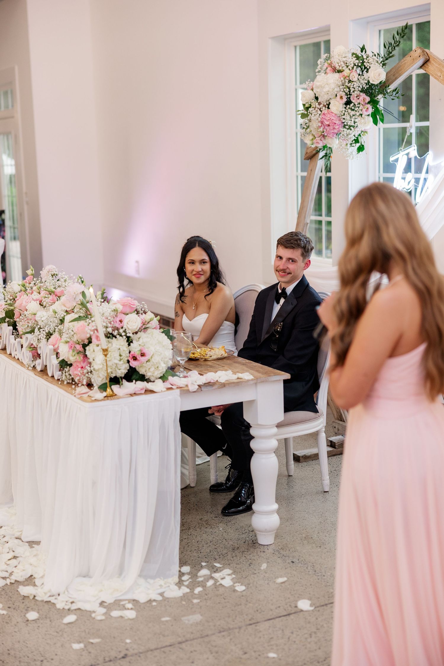 Wedding reception scene with pink bridesmaids dresses and white floral decorations.