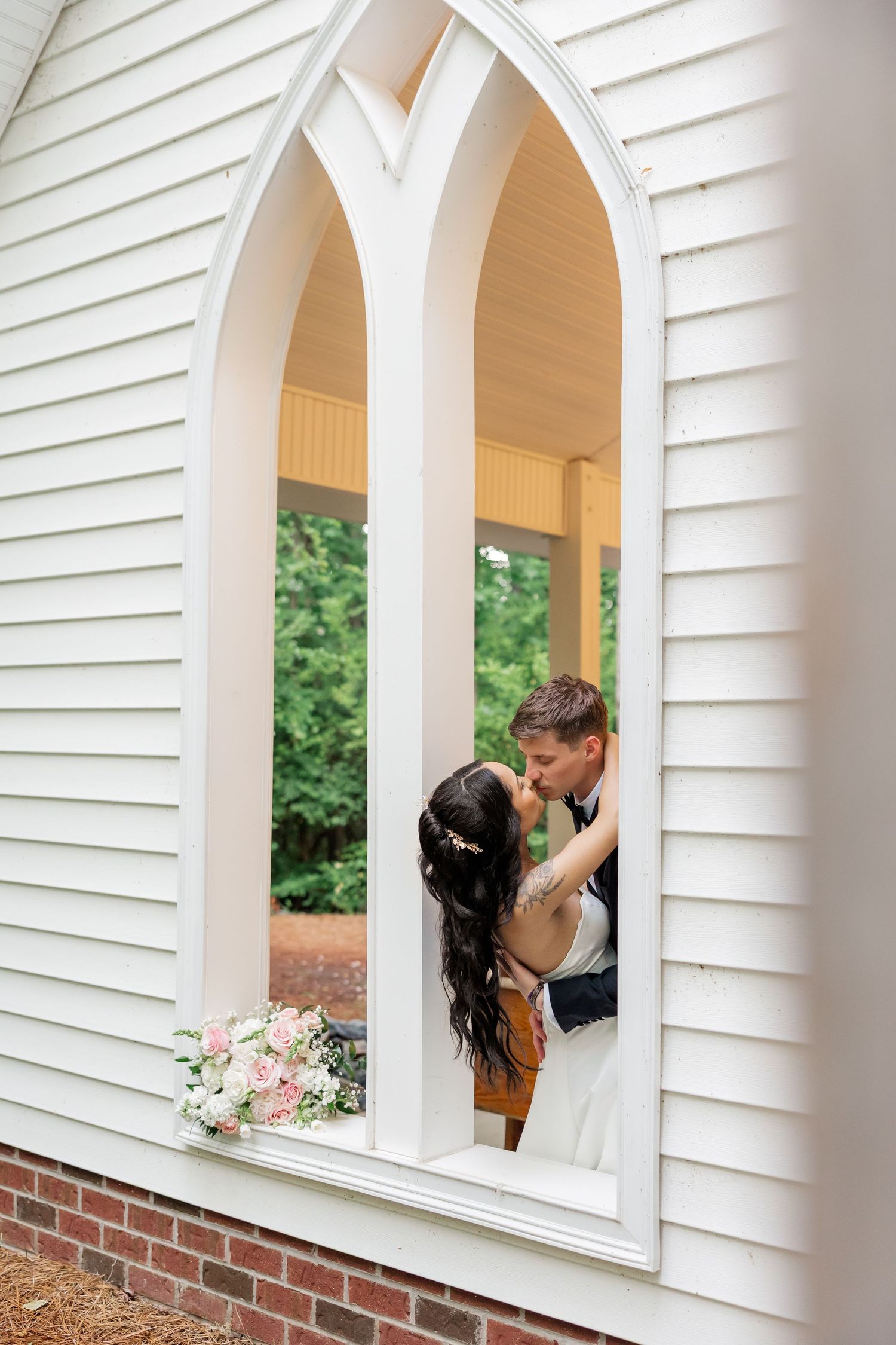 Artistic wedding photos framed through white arched windows of a chapel.