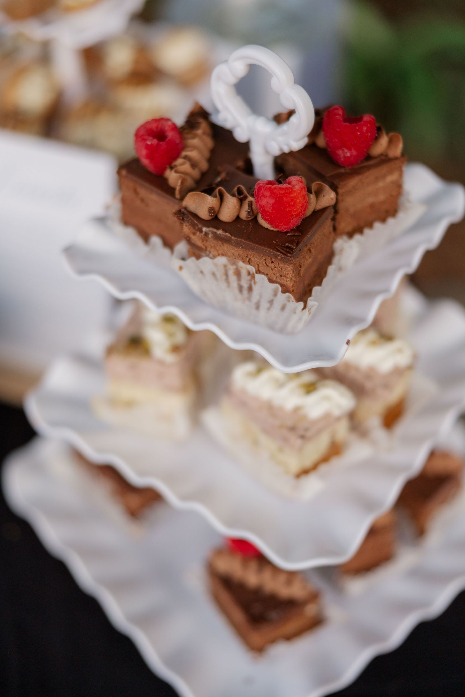 Chocolate desserts with fresh raspberries arranged on white scalloped plates.