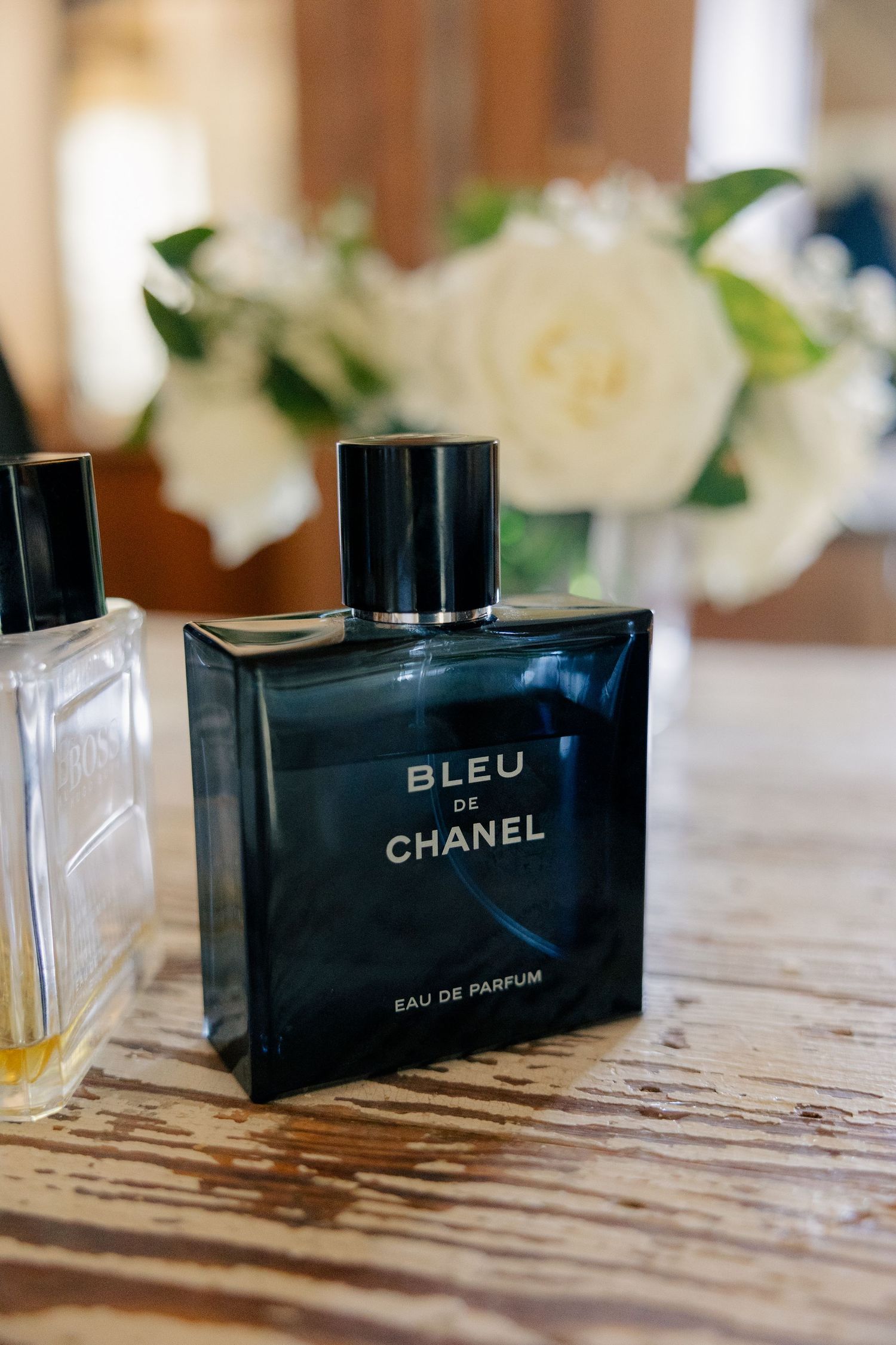 Black Chanel Bleu perfume bottles lined up on a rustic wooden surface.