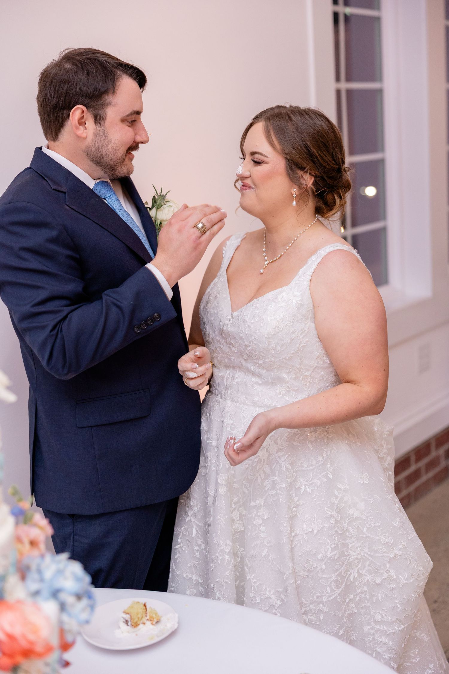 Couple shares cake-feeding moment during wedding reception.