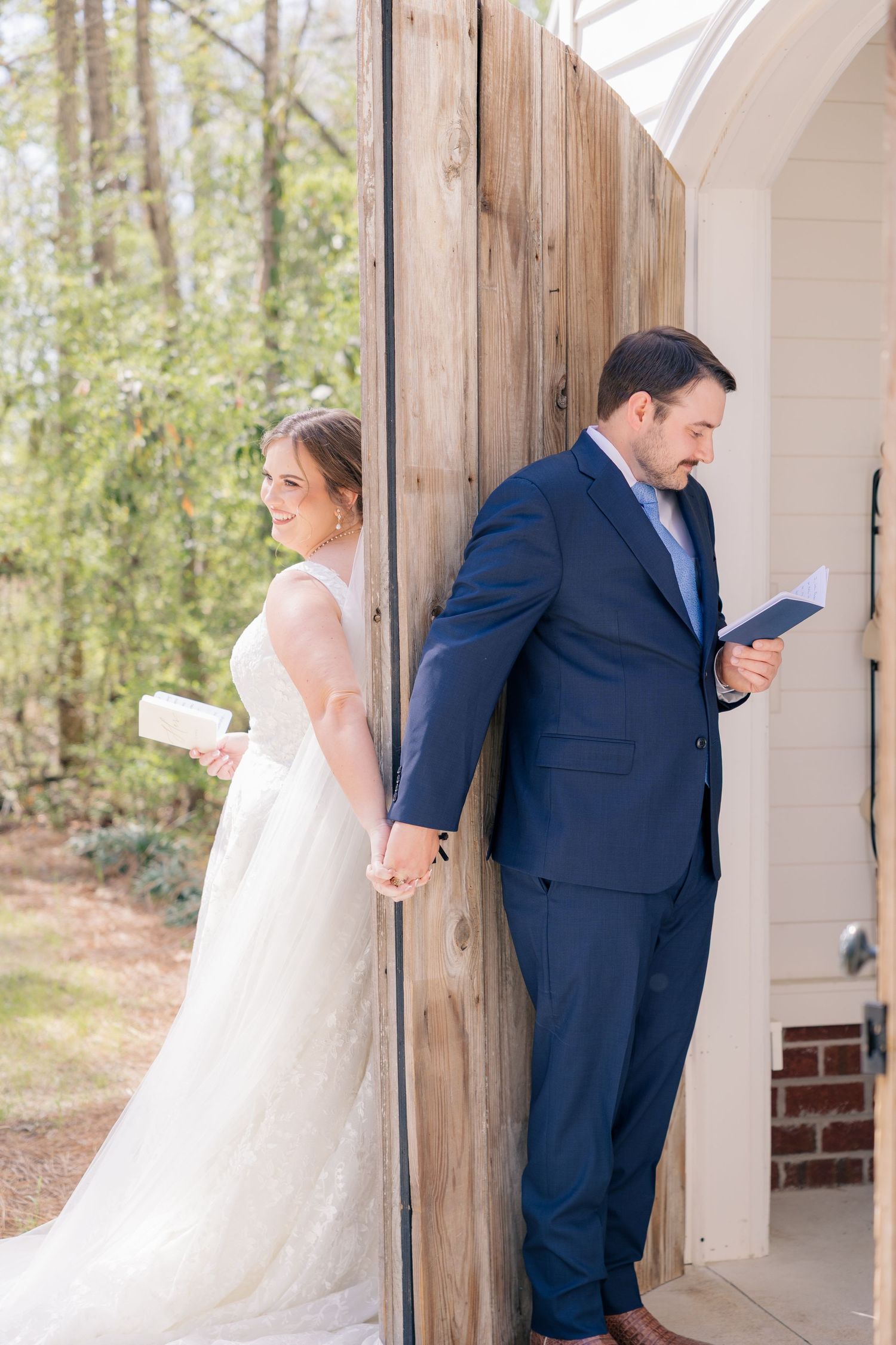 A couple standing together during their first look moment, with the bride in white and groom in navy blue.