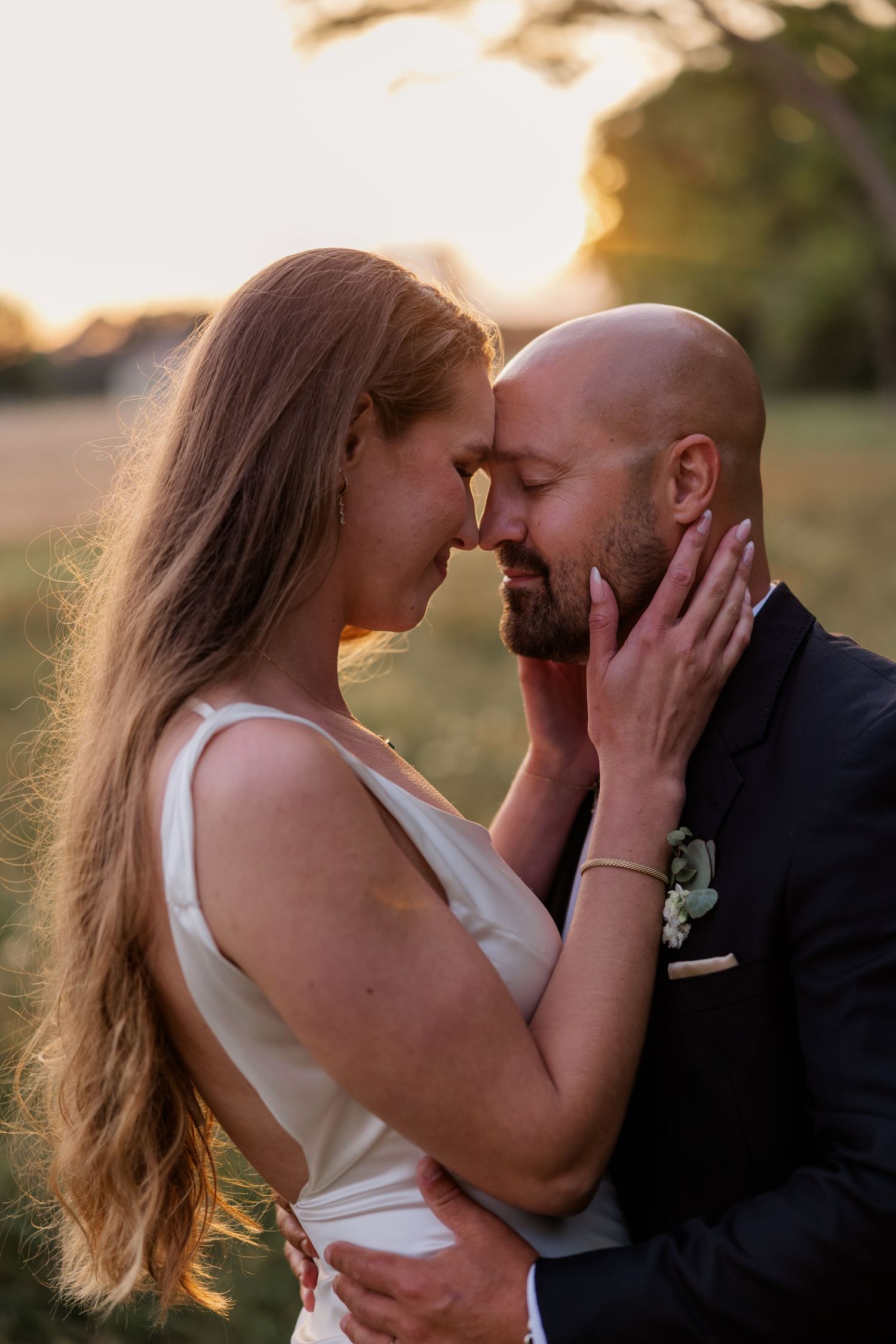 A romantic sunset portrait of a couple in wedding attire sharing an intimate moment.