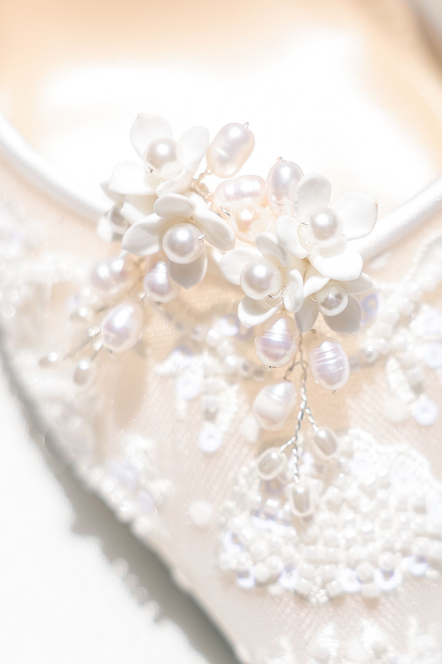 Delicate white pearls arranged in a floral pattern against a soft blurred background create an elegant bridal accessory.
