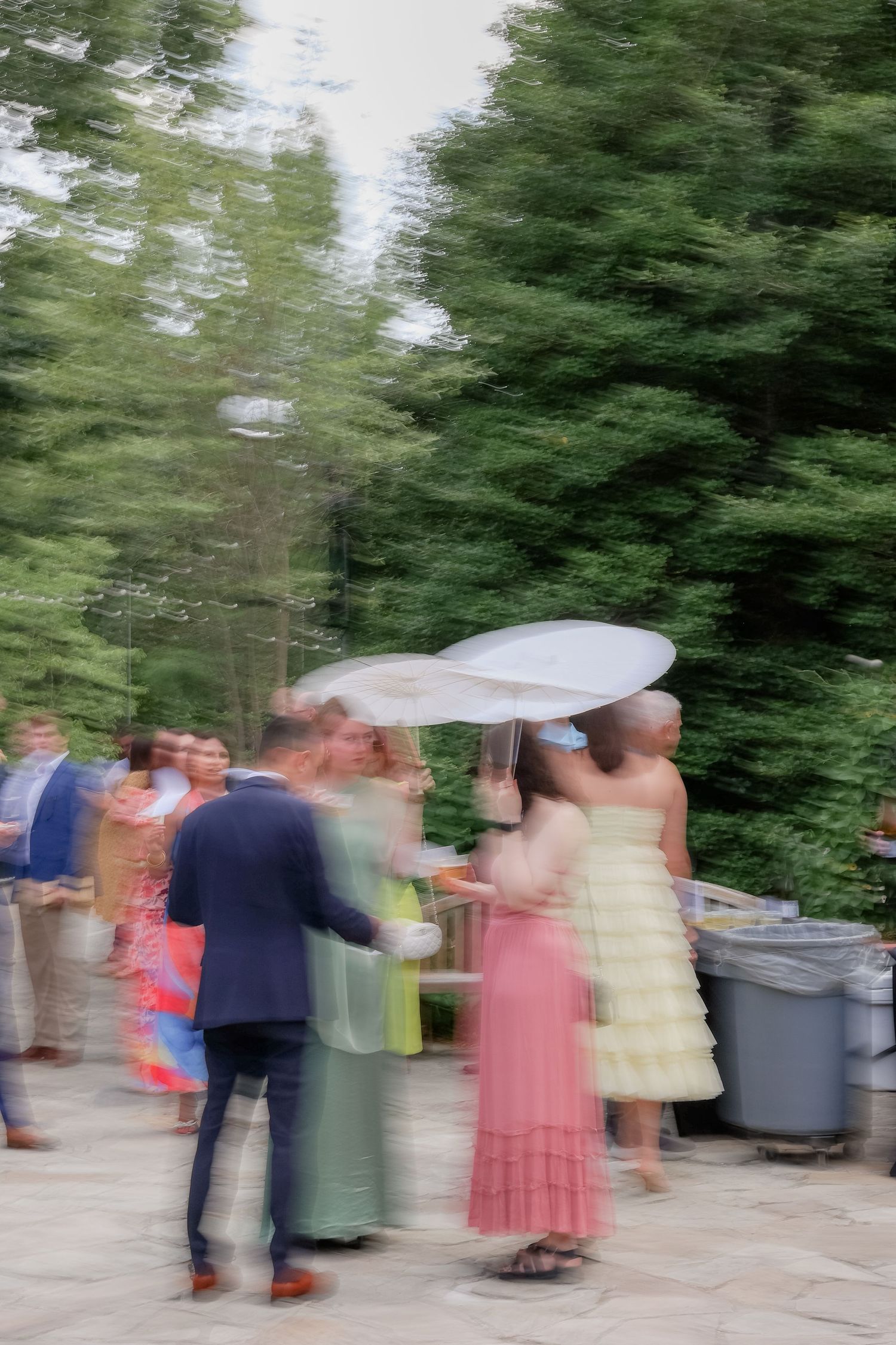 Motion-blurred wedding reception scene with guests mingling outdoors.