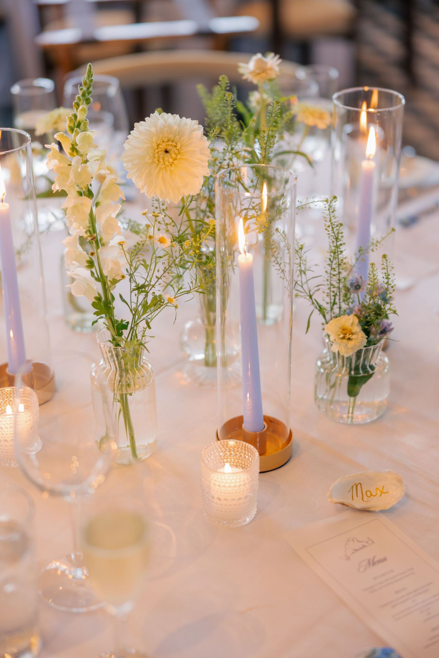 Romantic wedding tablescape with lavender taper candles, yellow dahlias, wildflowers in bud vases, and menus.