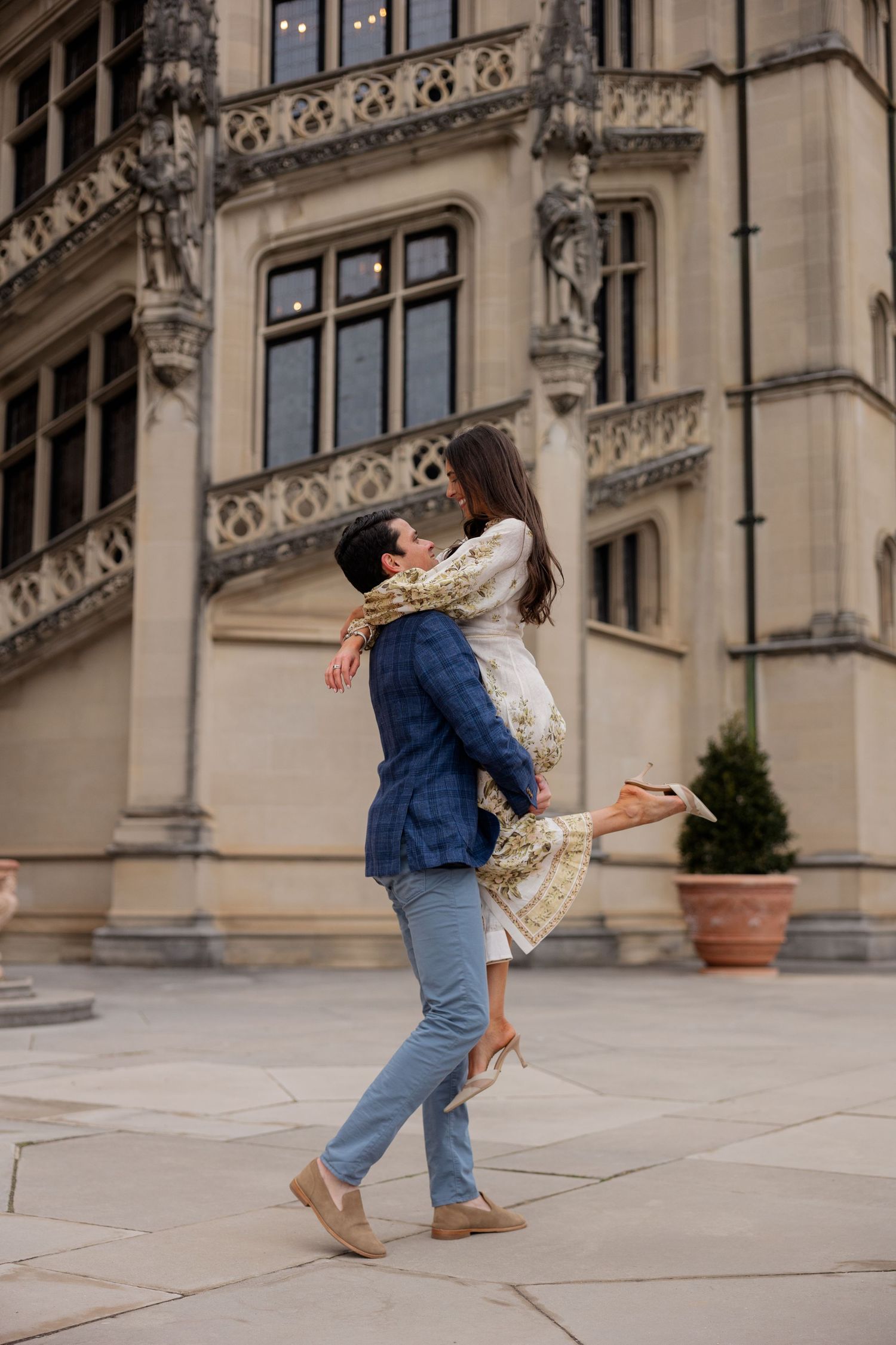 A romantic embrace at a grand historic building as a couple share a joyful lift in elegant attire.