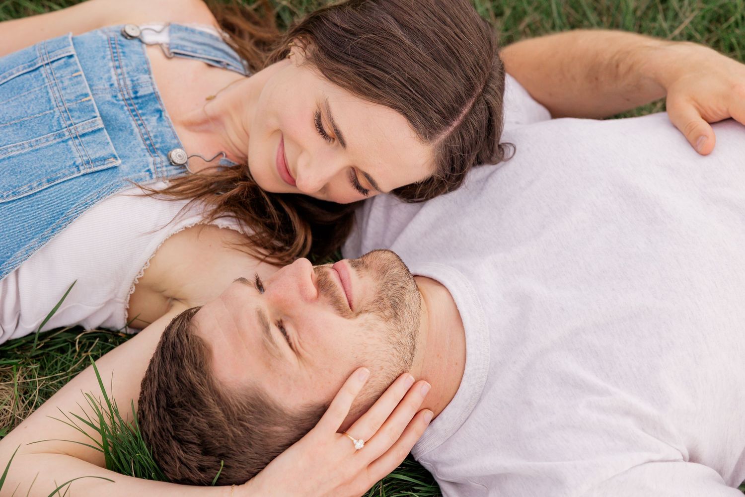 A romantic couple lying on grass in white clothing sharing tender kisses in a series of connected photos.