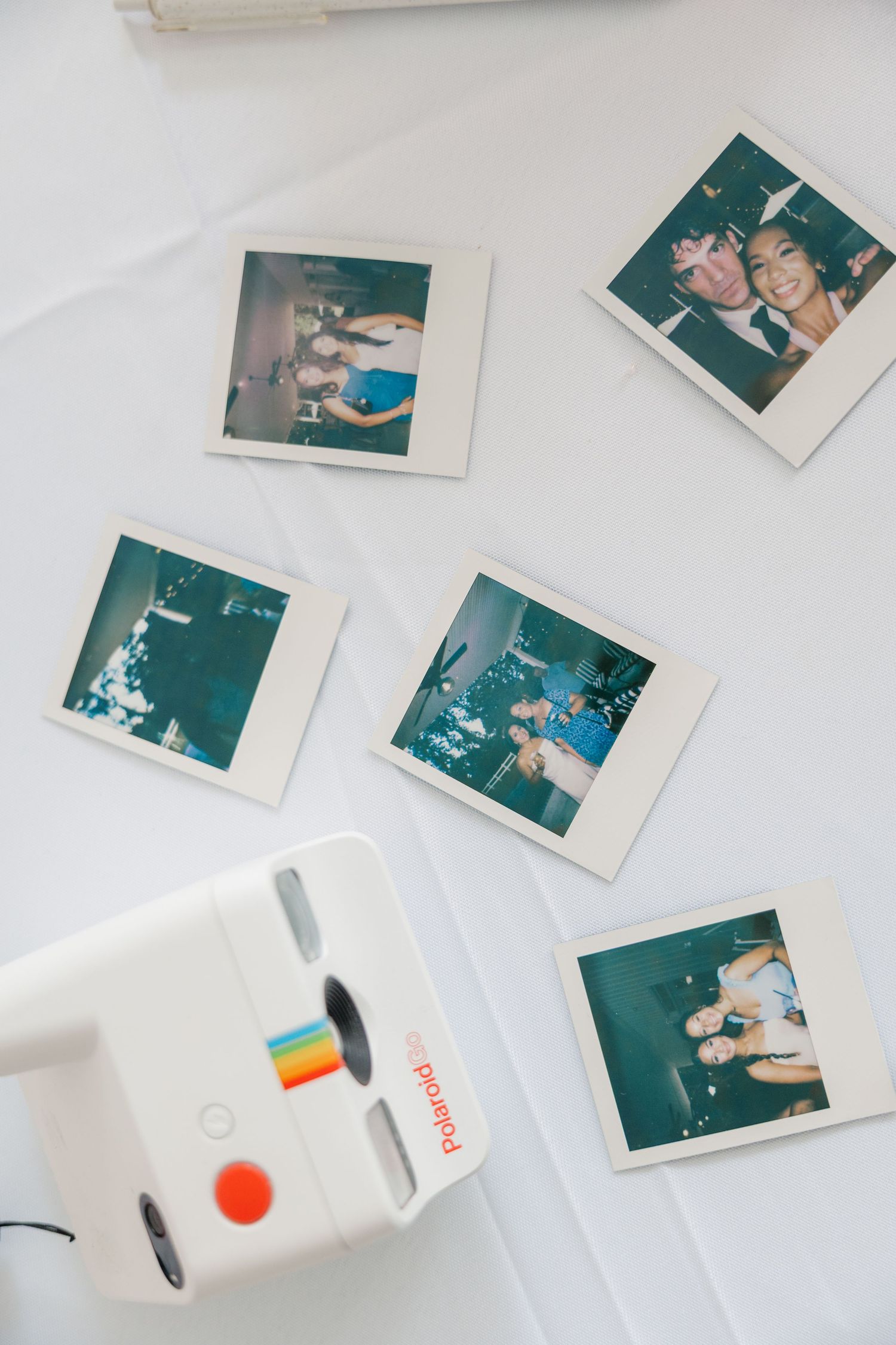 Polaroid instant photos and camera scattered on white surface capturing wedding moments.