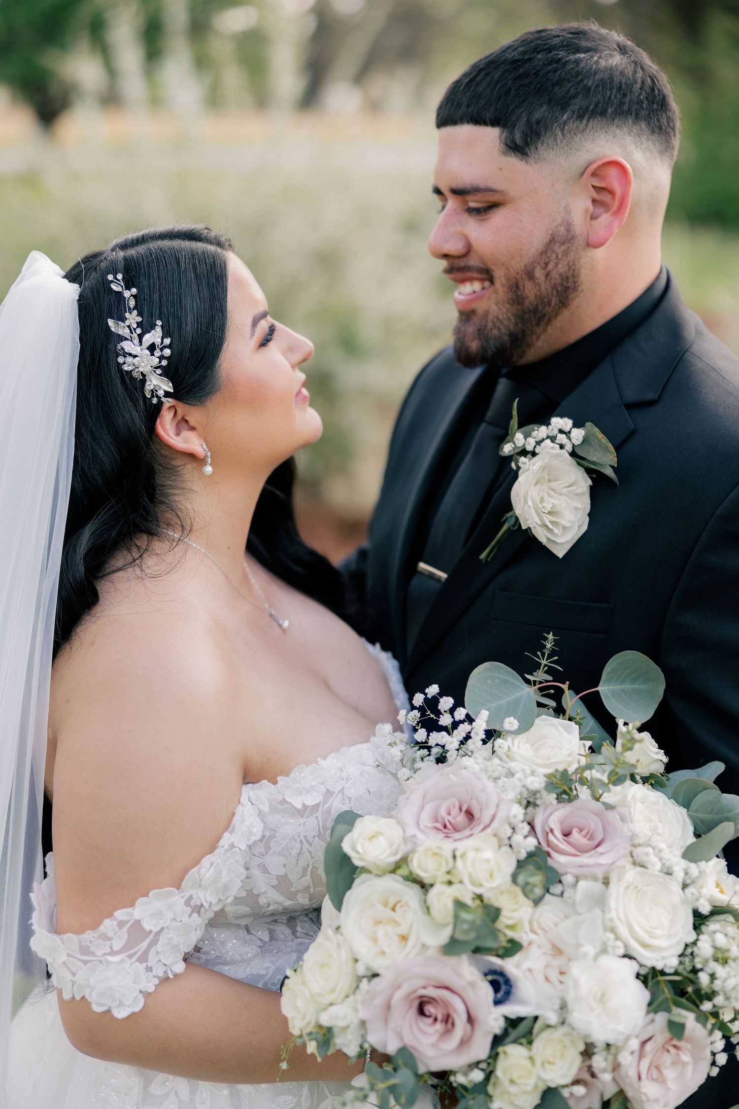 A joyful wedding portrait featuring a couple sharing a candid moment with a beautiful white and pink rose bouquet.