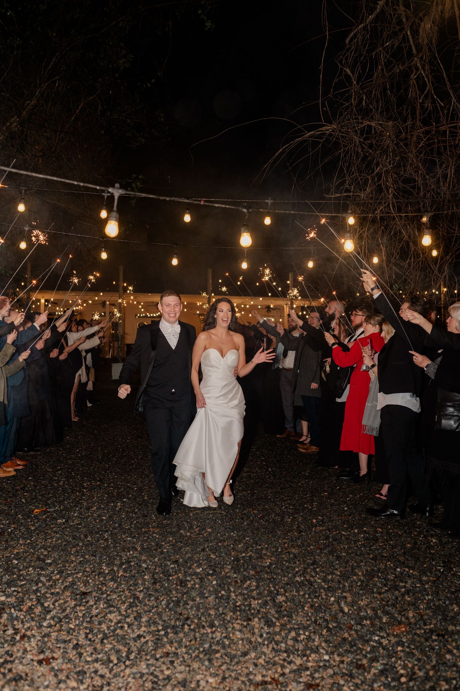 Wedding guests celebrate under outdoor string lights during an evening reception.