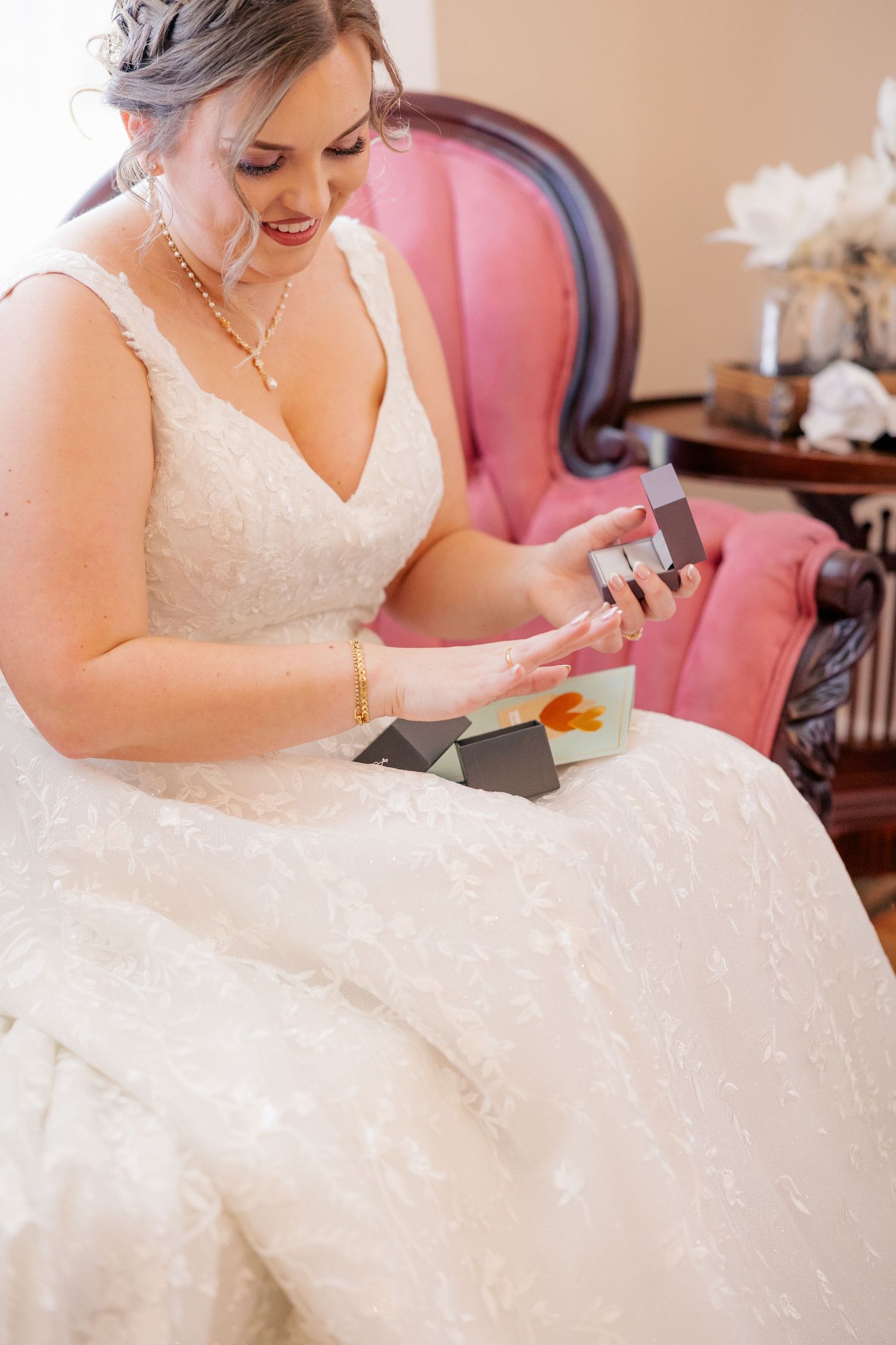 Close-up detail of a bride in her wedding dress looking at something in her hands.
