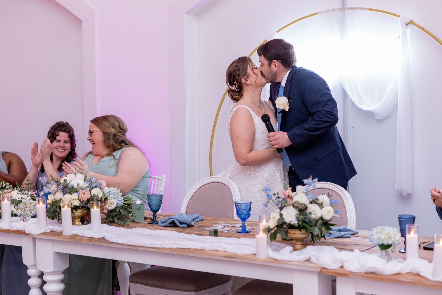 Wedding reception table with pink lighting and elegant place settings.