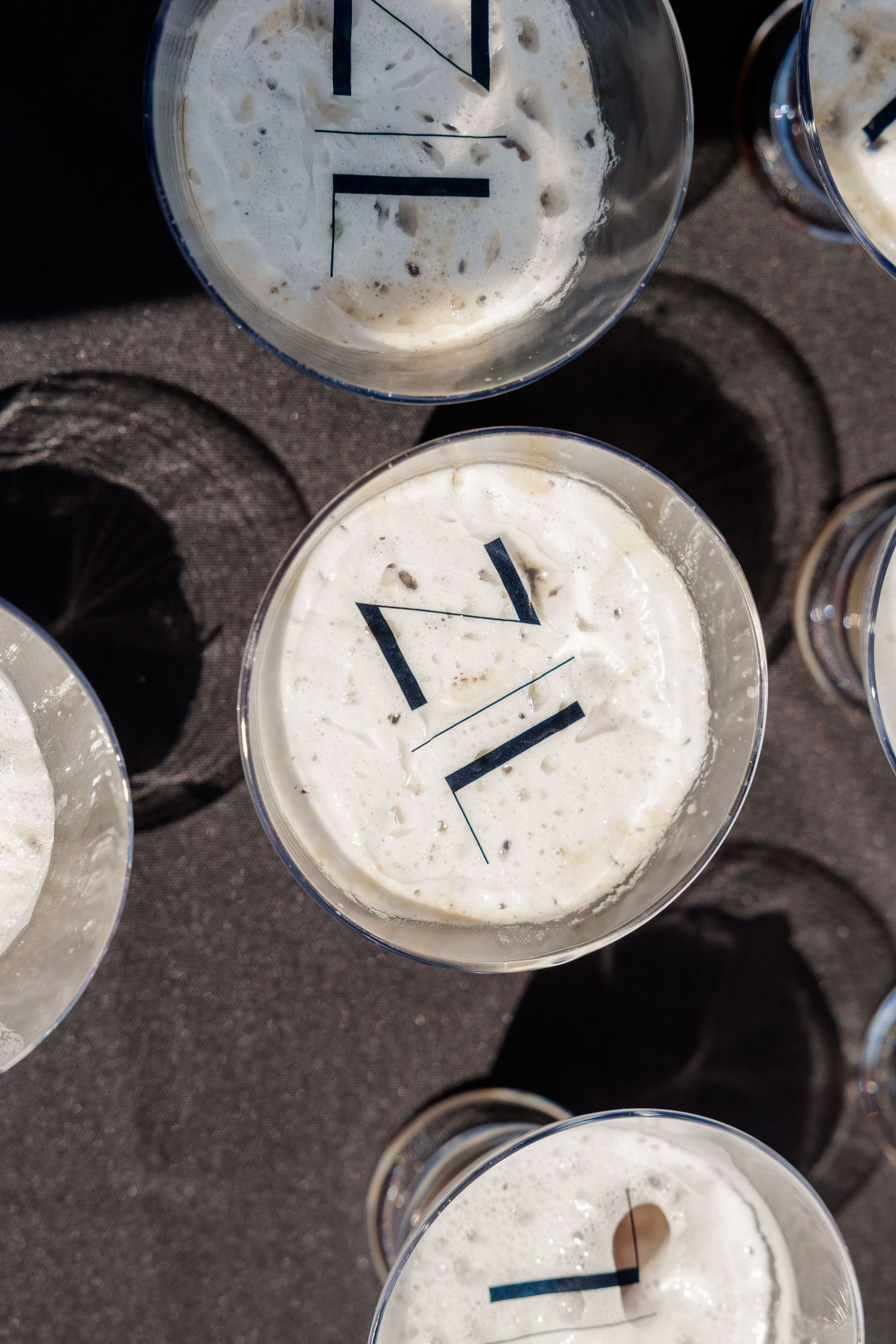 White candles with black wicks sit in glass holders on a dark surface.