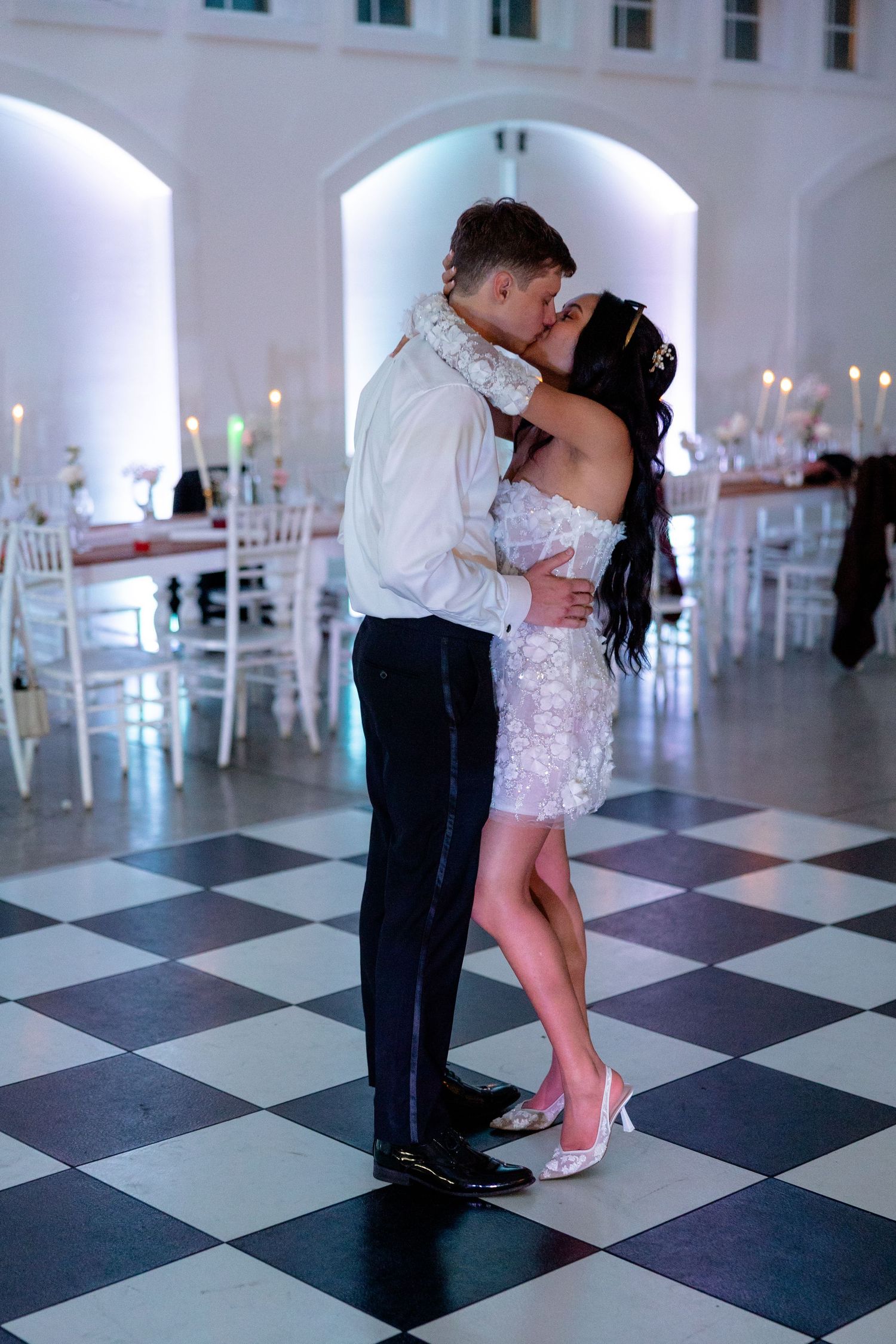 Romantic dance moment on black and white checkered floor under arched ceiling.
