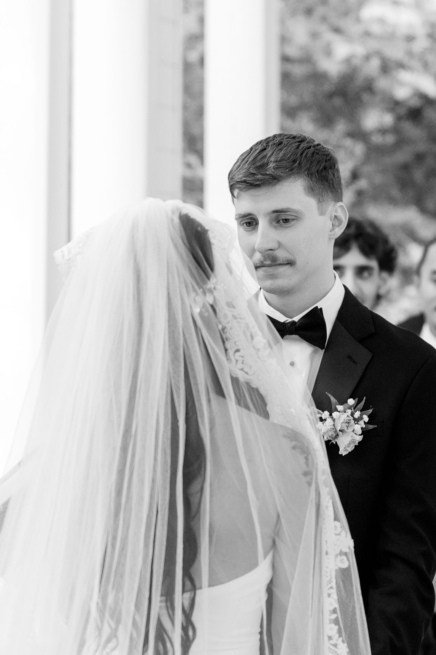 Romantic wedding moment captured under white pillars with soft natural lighting.