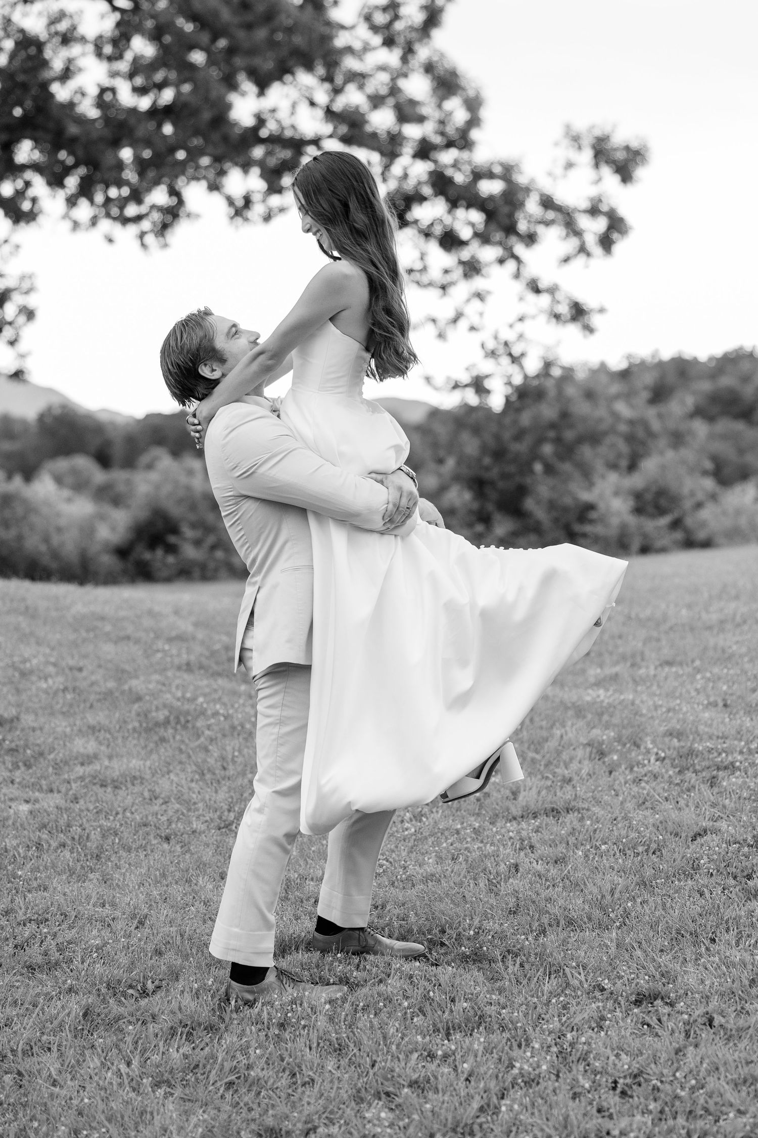 Black and white sequence of two people dancing playfully on a grassy hillside.