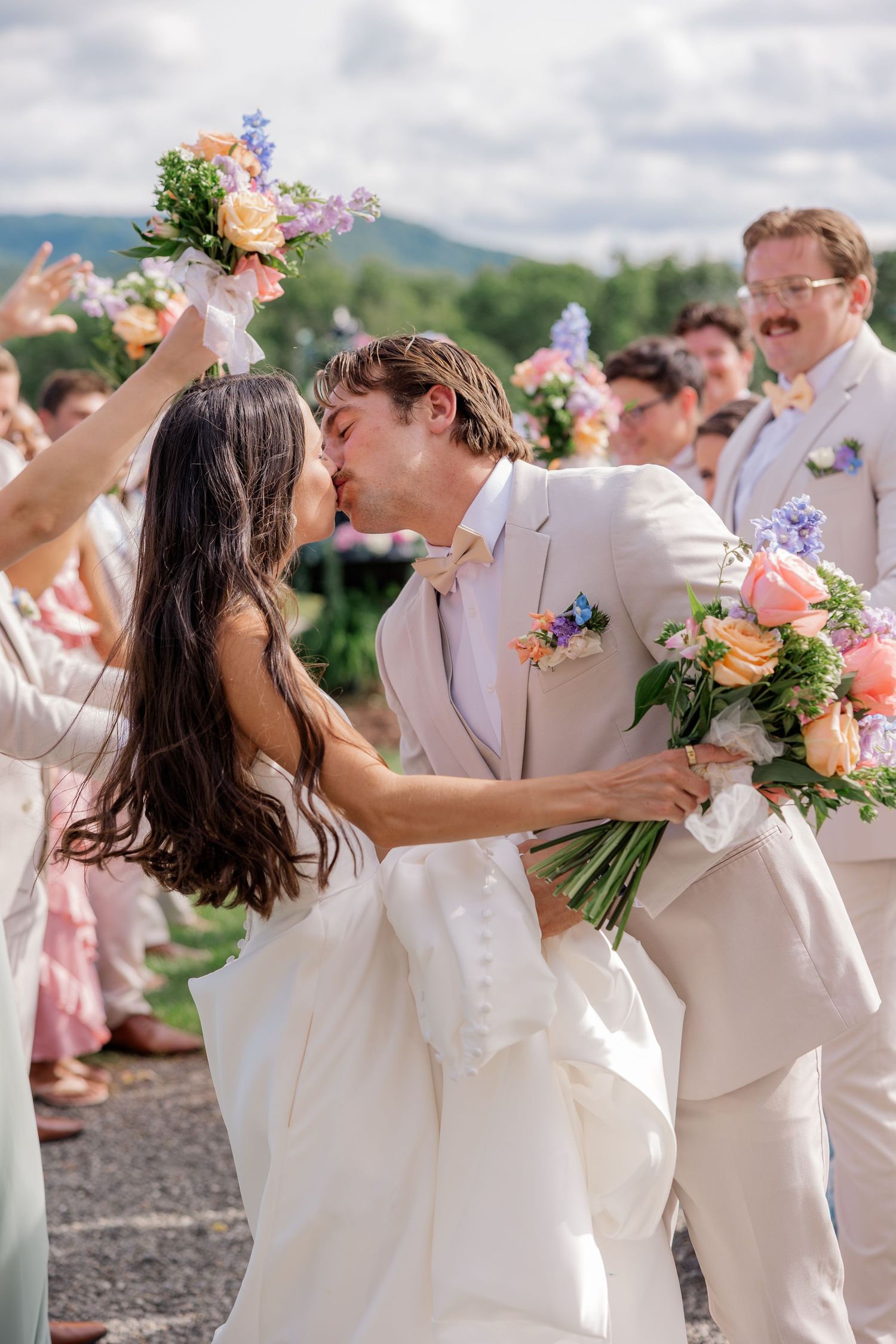 Wedding celebration with couples dancing in white attire surrounded by colorful bouquets.