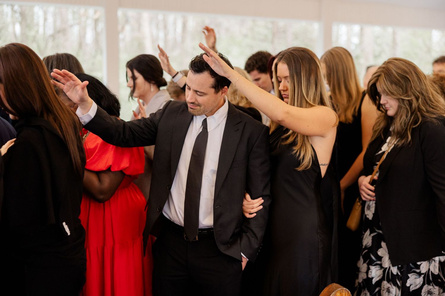 Wedding reception guests dancing and celebrating with raised arms.