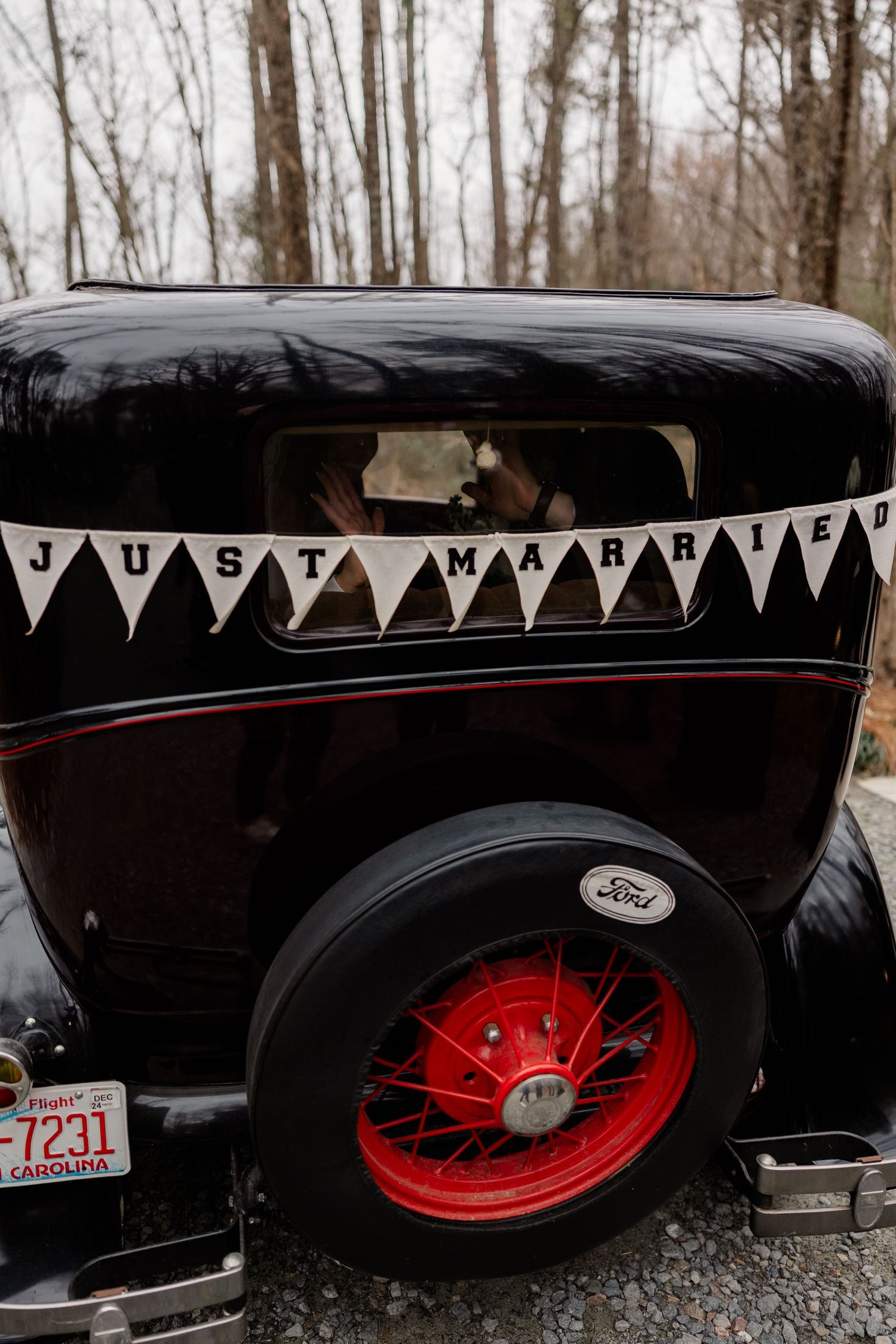 Vintage black Ford car with red wheels and 'Just Married' bunting displayed at wedding.