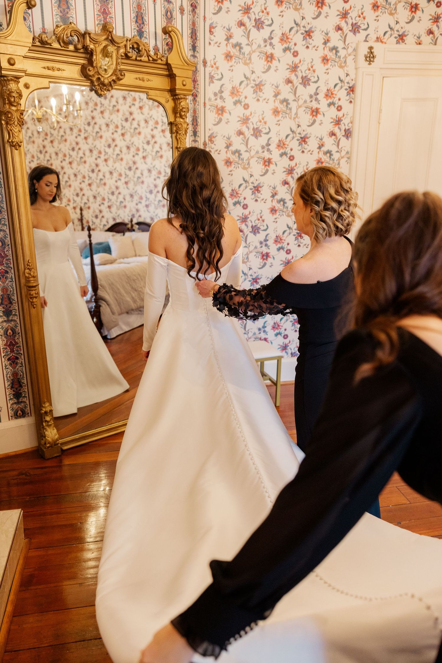Elegant bridal suite with floral wallpaper and ornate gold mirror where a bride prepares for her wedding day.