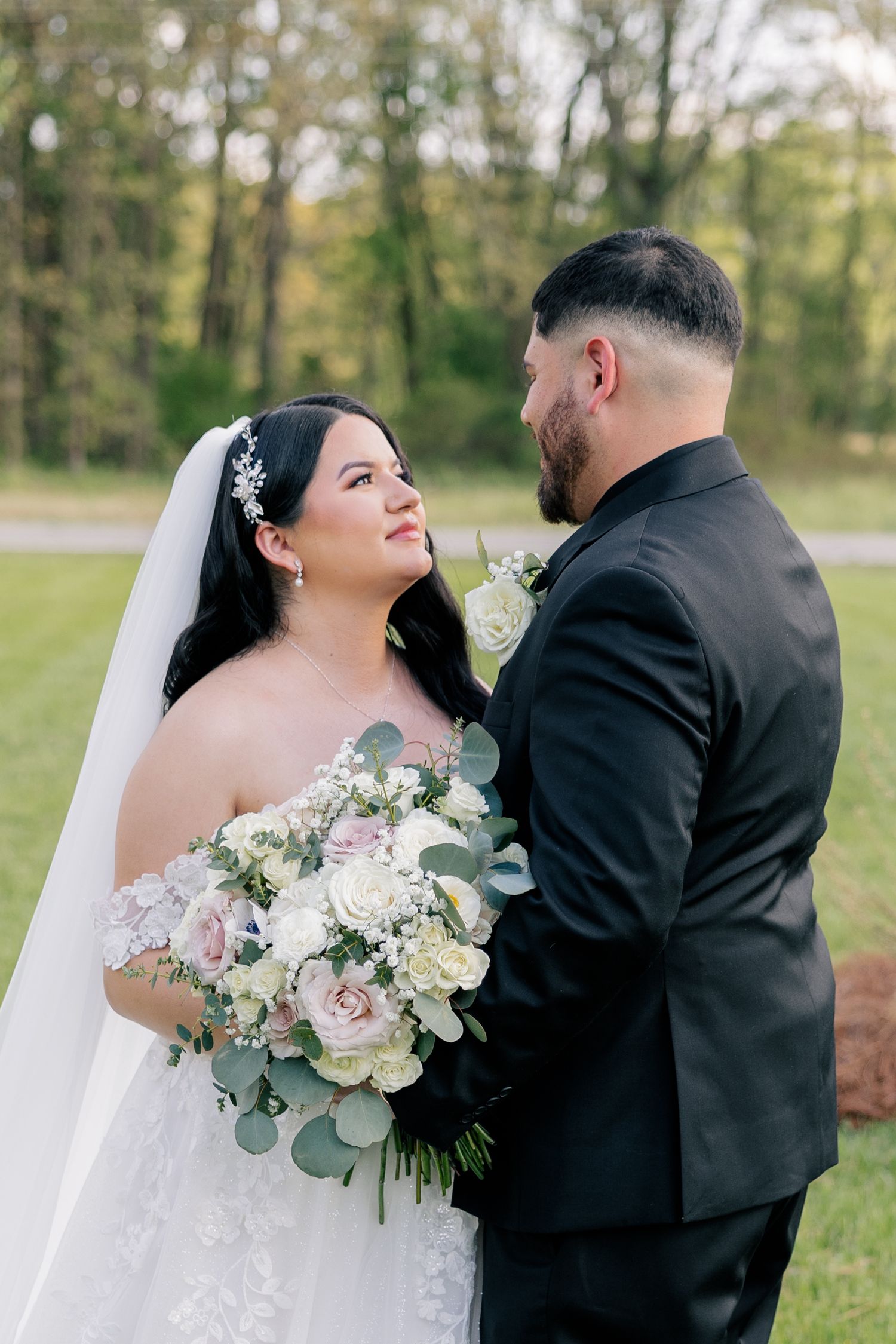 Wedding couple shares intimate moments outdoors with the bride holding a lush white and green floral bouquet.
