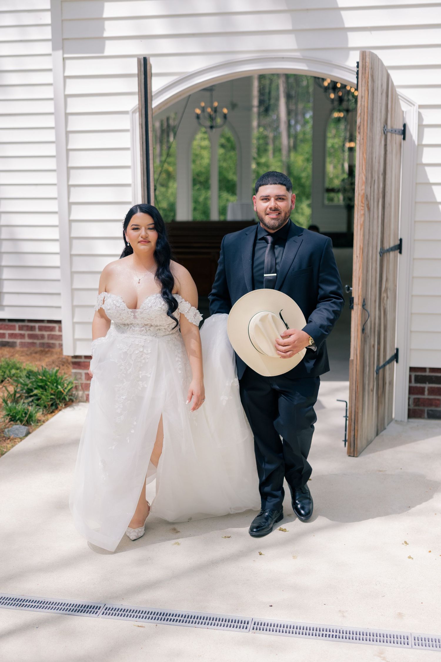 Wedding couple shares candid moments on white porch with rustic wooden details.