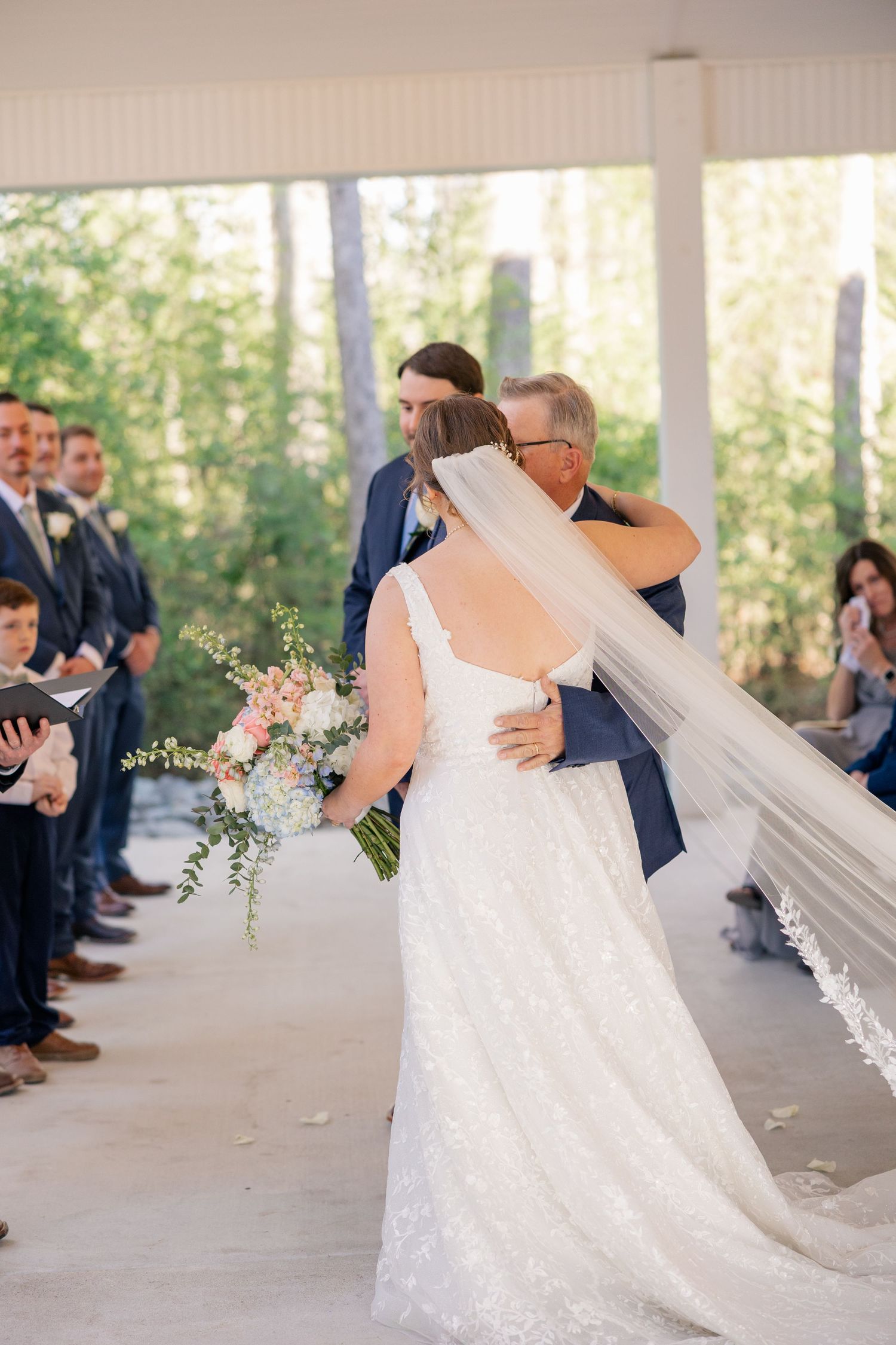 Wedding ceremony moments captured in a bright chapel with elegant decor and navy-suited guests.