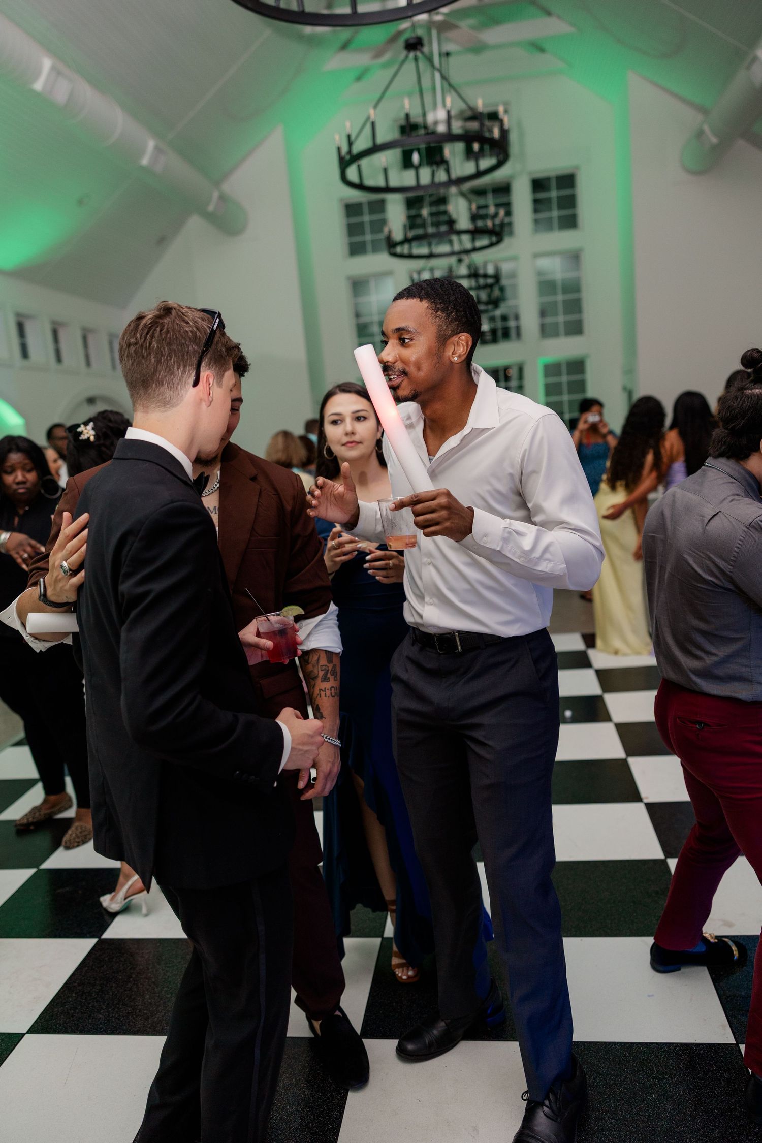 Wedding guests socializing during reception under green ambient lighting.