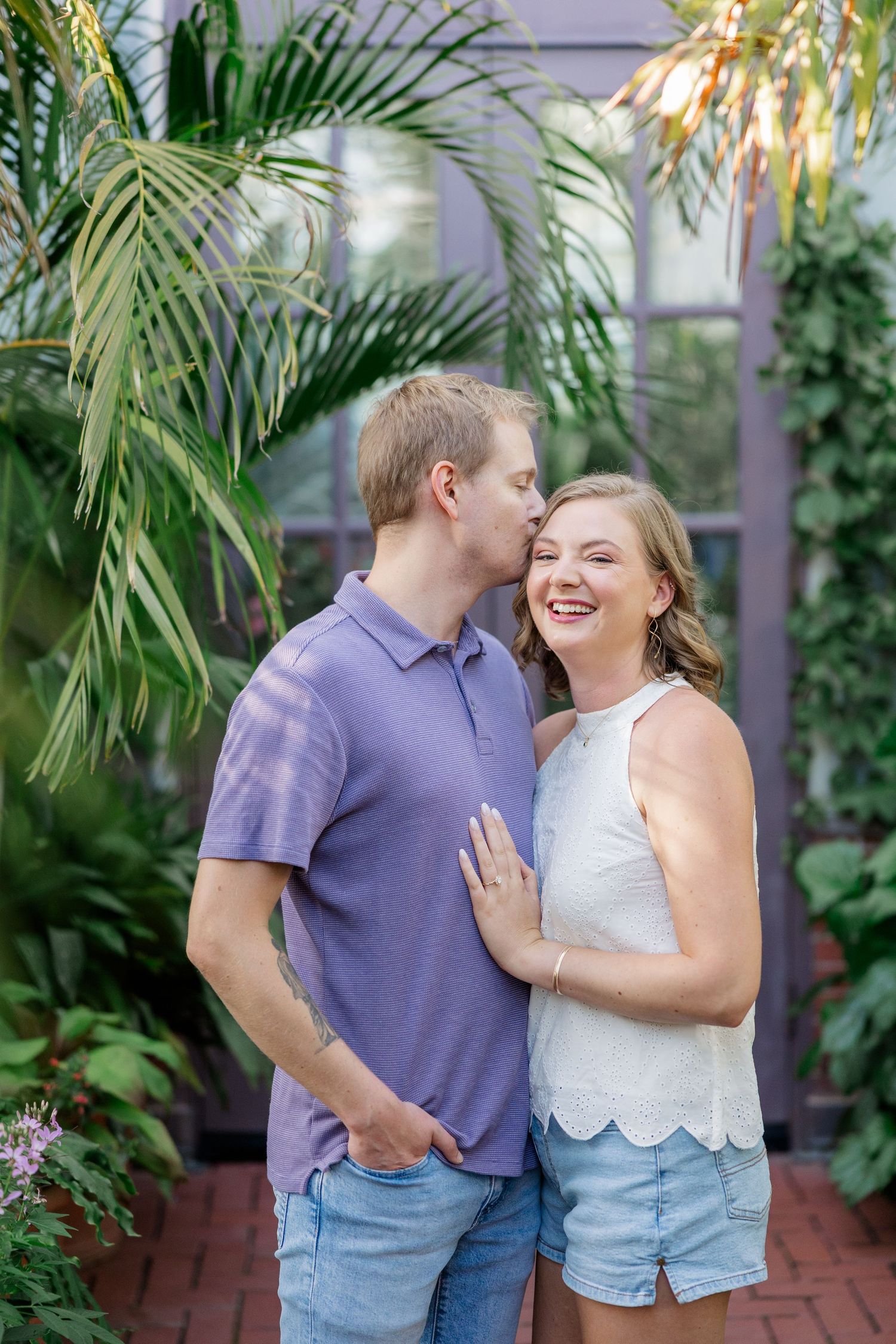 A couple shares joyful moments together against a backdrop of tropical palm plants.
