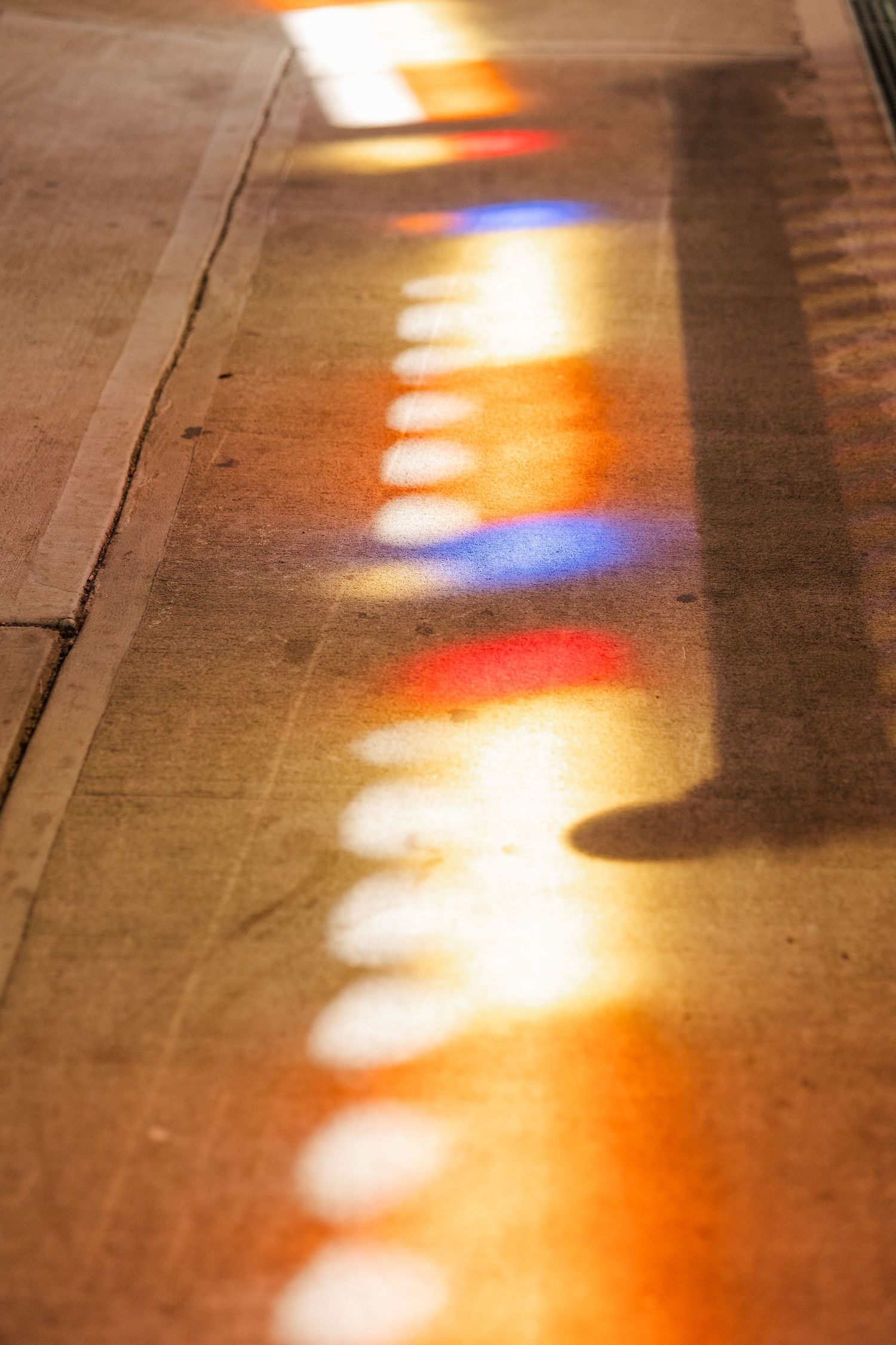 Colorful stained glass light reflections casting red, blue, and white patterns on a stone floor.