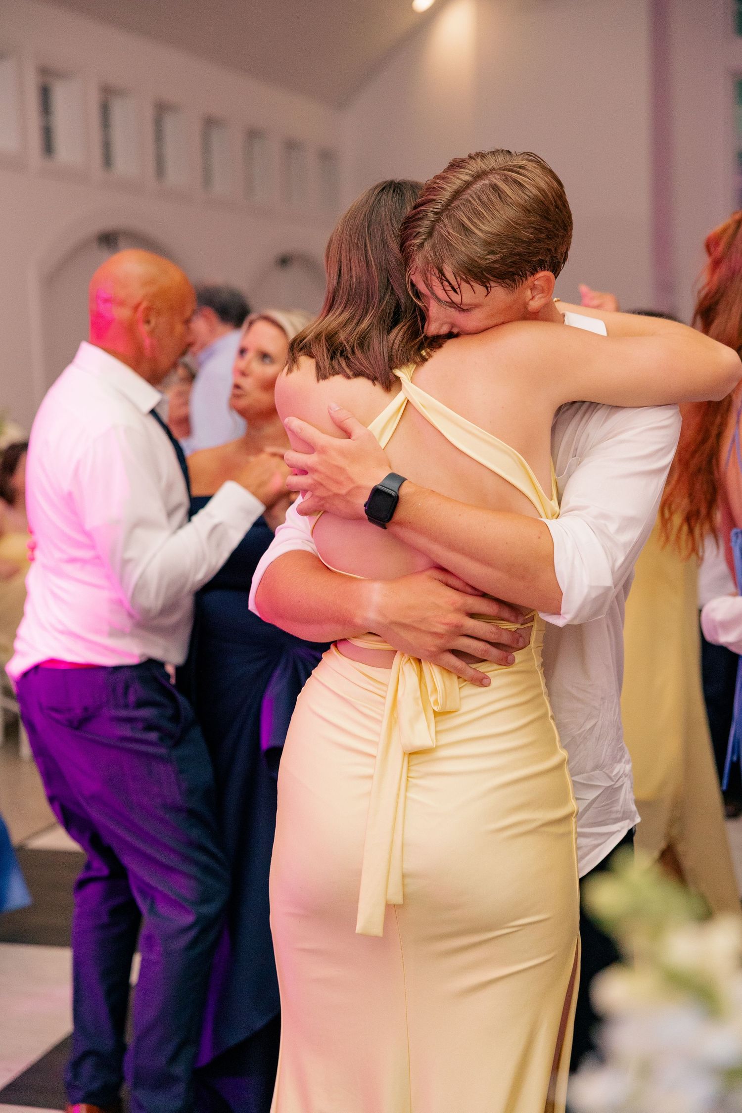 Couple sharing an embrace while dancing at elegant indoor wedding reception.