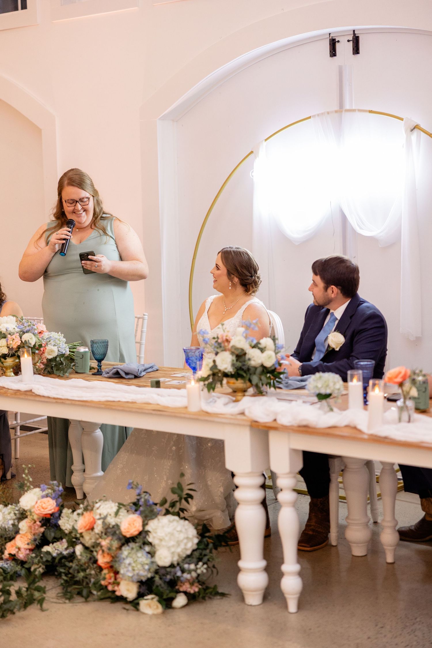 Wedding reception venue with white pillars and floral garland decorations along an elegant dining table.