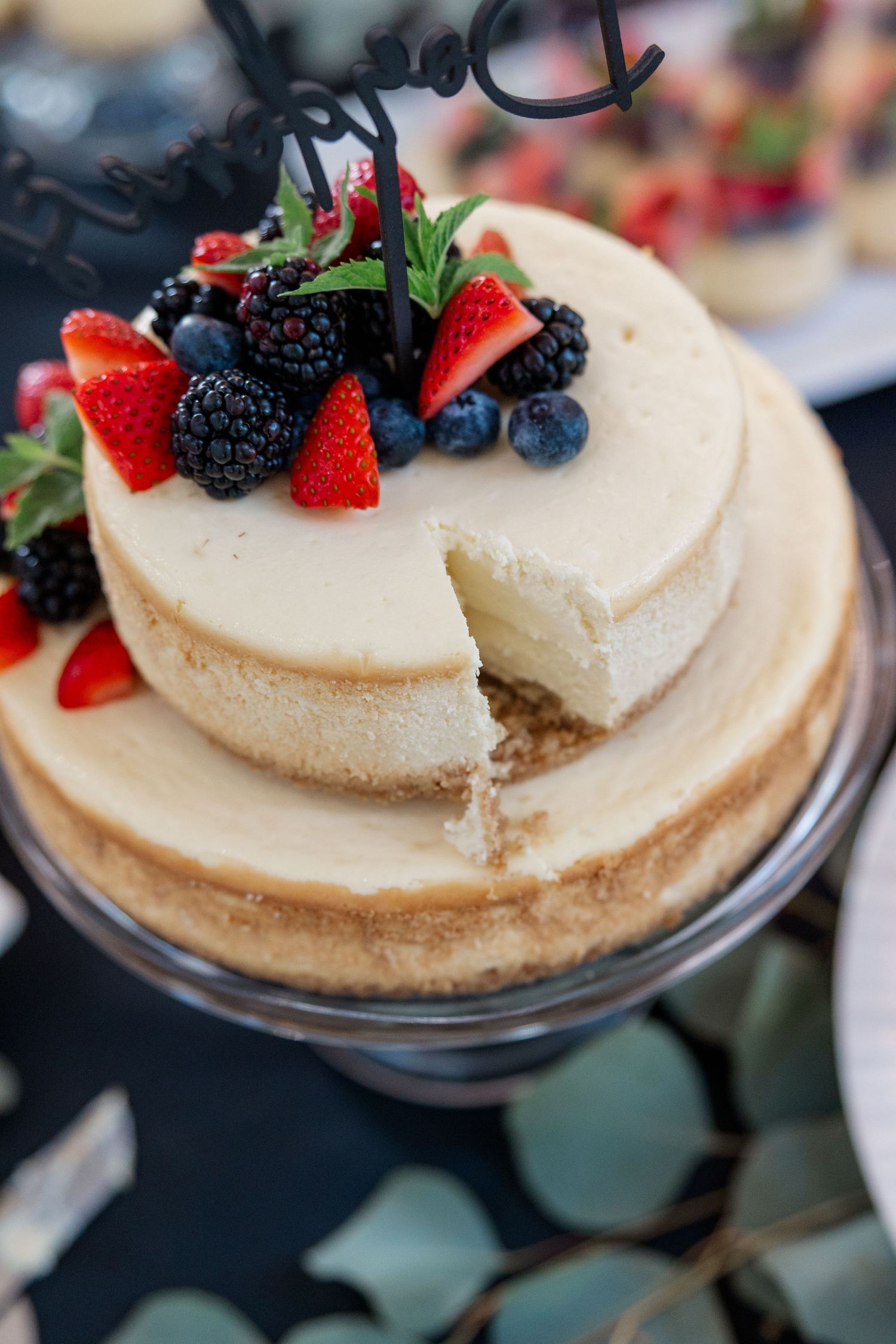 Close-up of cheesecake topped with fresh berries and fruit at a wedding reception.