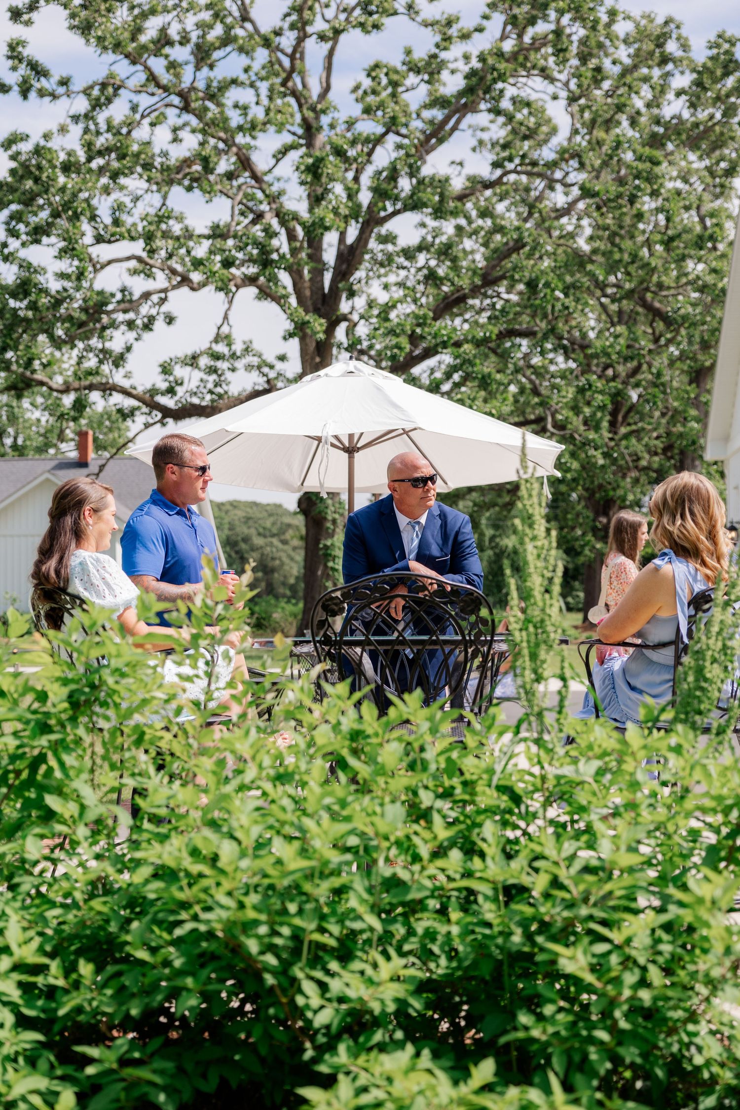 Outdoor garden party setup with white tent and greenery in natural setting.