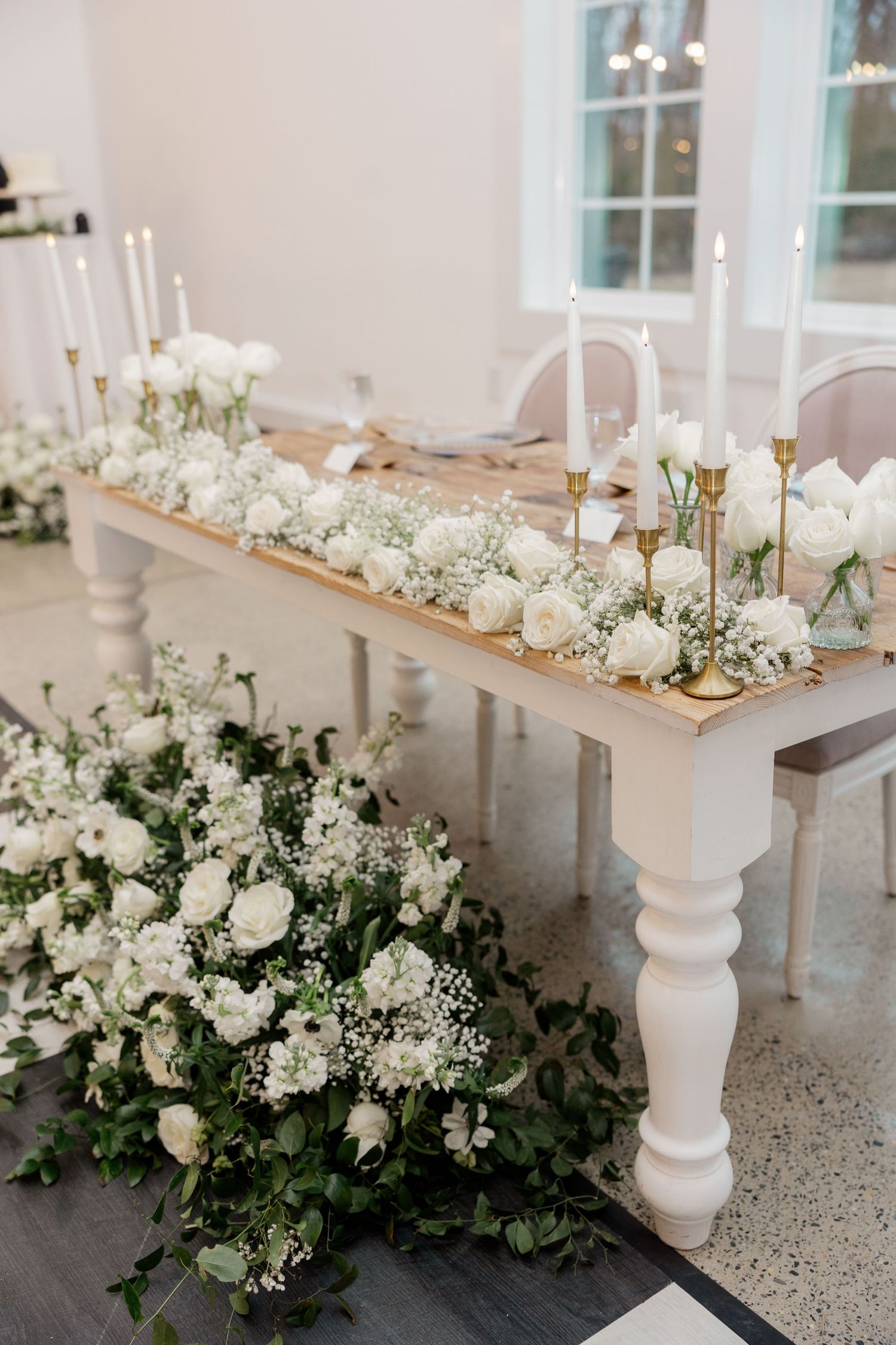 Elegant wedding table decorated with white flowers, candles, and baby's breath centerpieces on a rustic wooden surface.