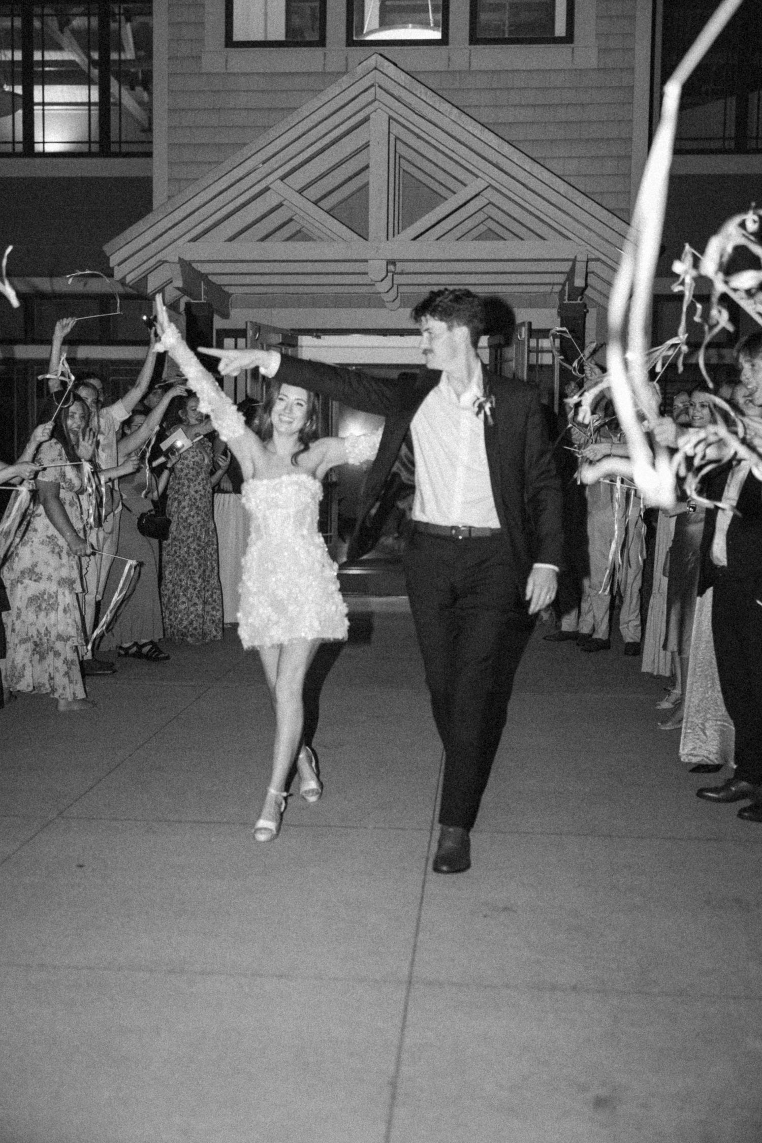 Black and white photo of wedding guests dancing and celebrating at an evening reception.