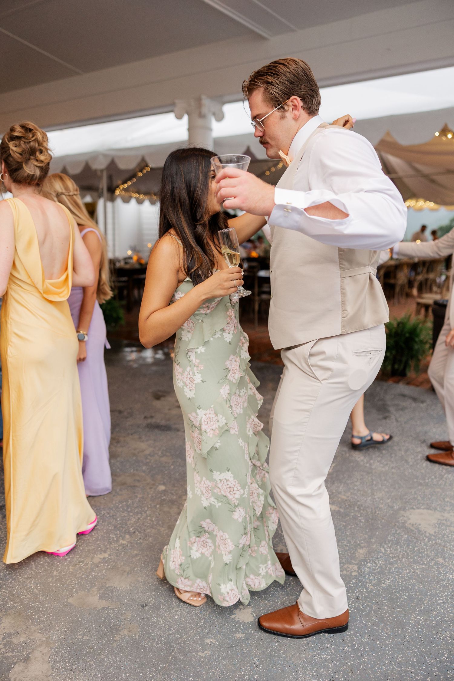 Wedding reception dance sequence showing guests in yellow and floral dresses dancing with others in light suits.