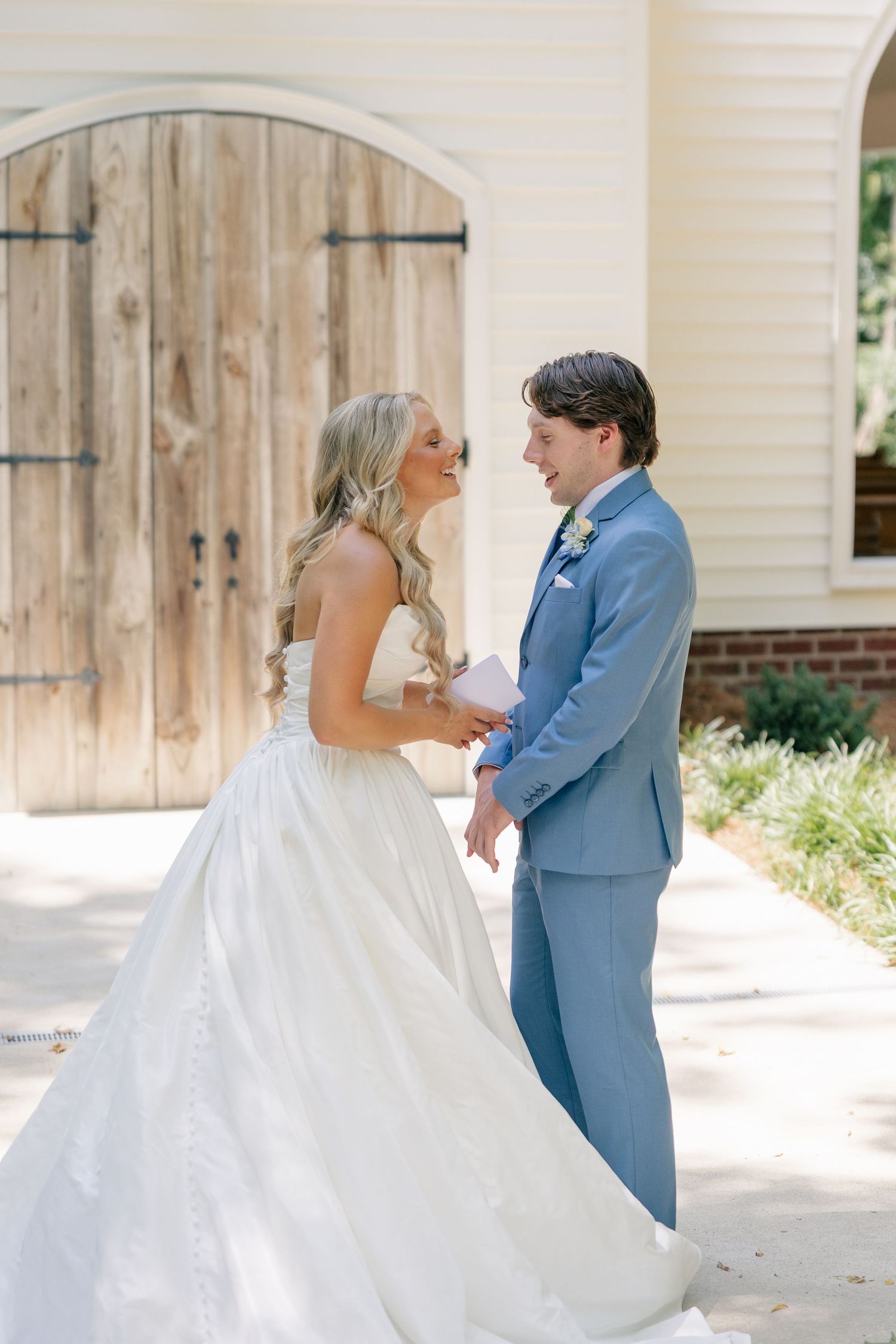 Bride and groom share a joyful first look moment outside a rustic chapel on their wedding day.
