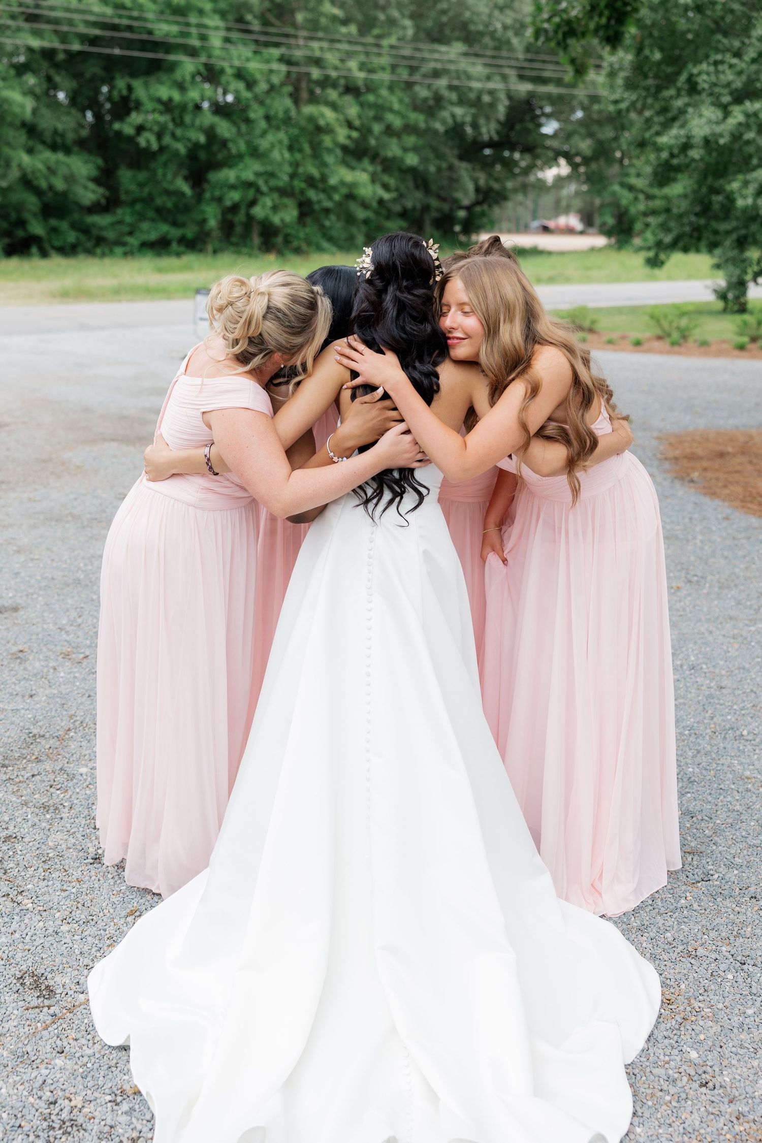 Wedding party enjoying candid laughter together in pink and white dresses outdoors.