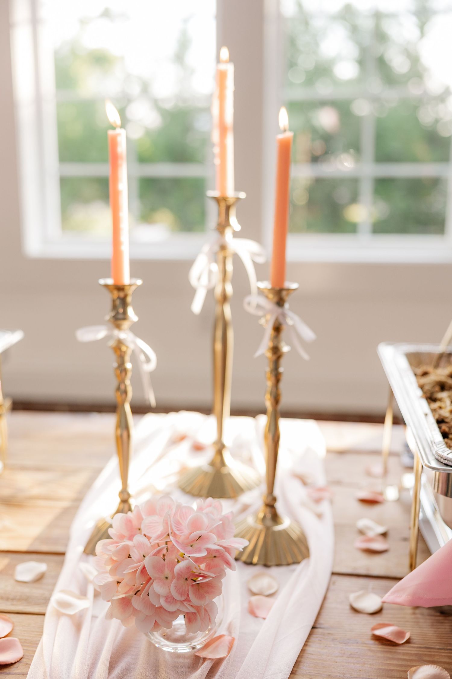 Elegant wedding table setting with gold candlesticks and pink floral arrangements.