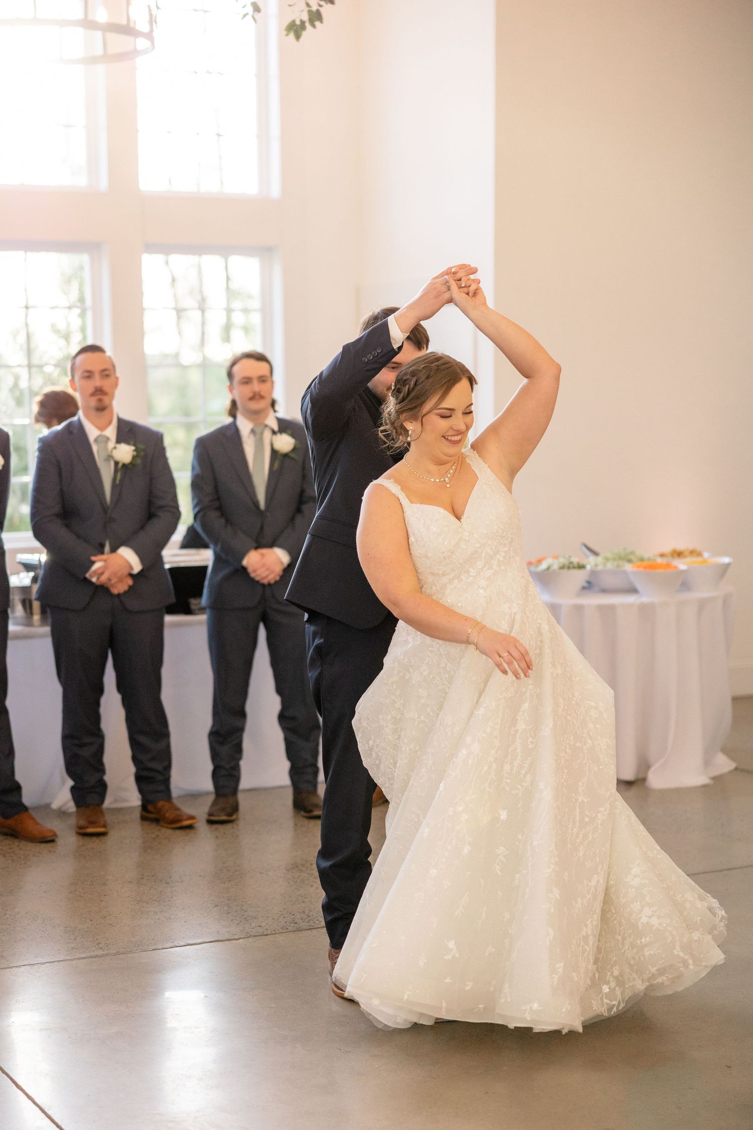 Wedding party dancing and twirling in a bright reception hall.
