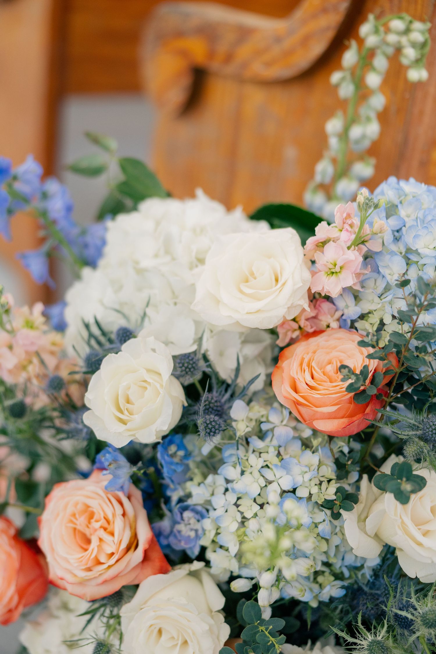 Elegant floral arrangement featuring peach and white roses with blue accents and delicate greenery.