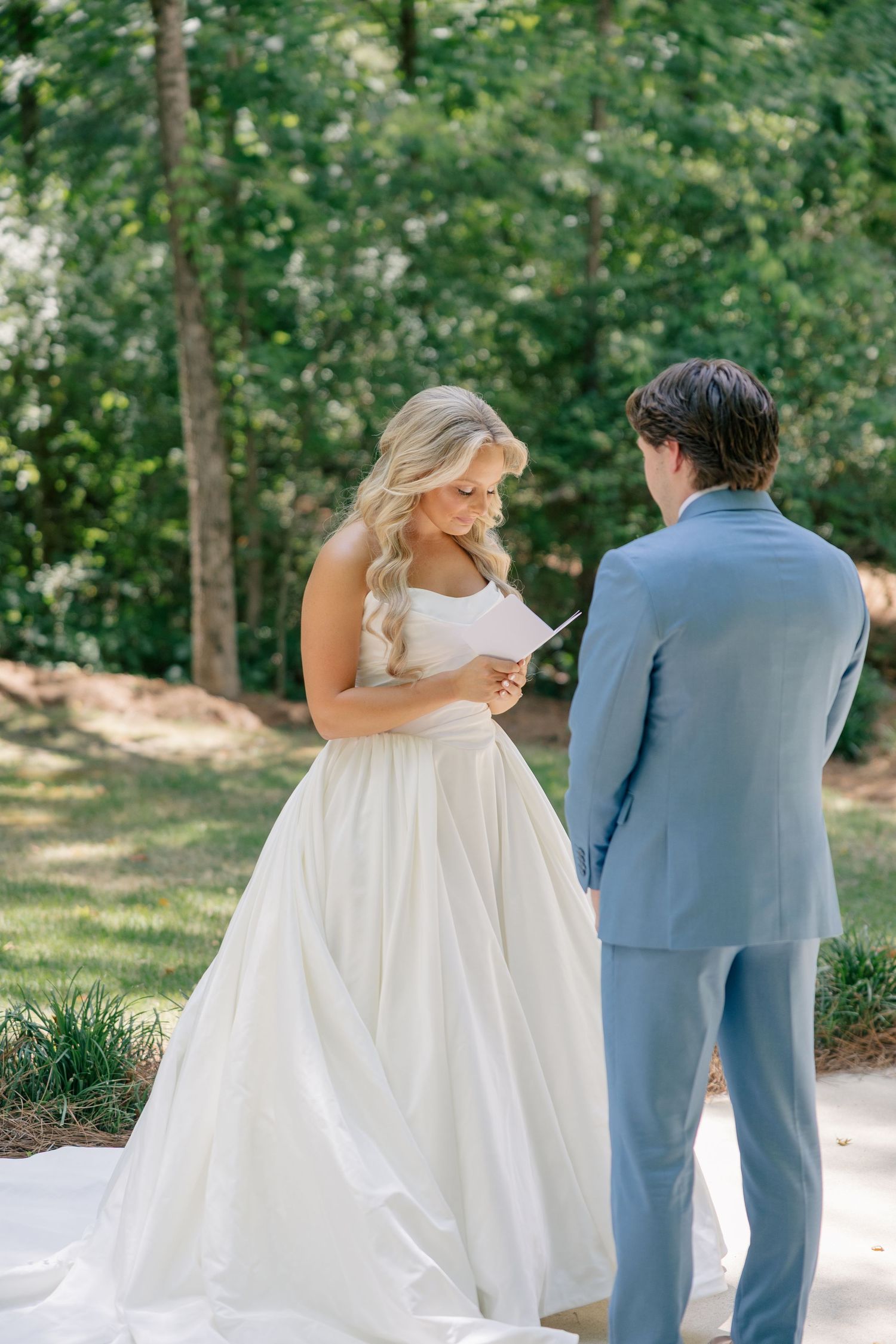 Bride reading handwritten vows to groom during an intimate outdoor first look ceremony.