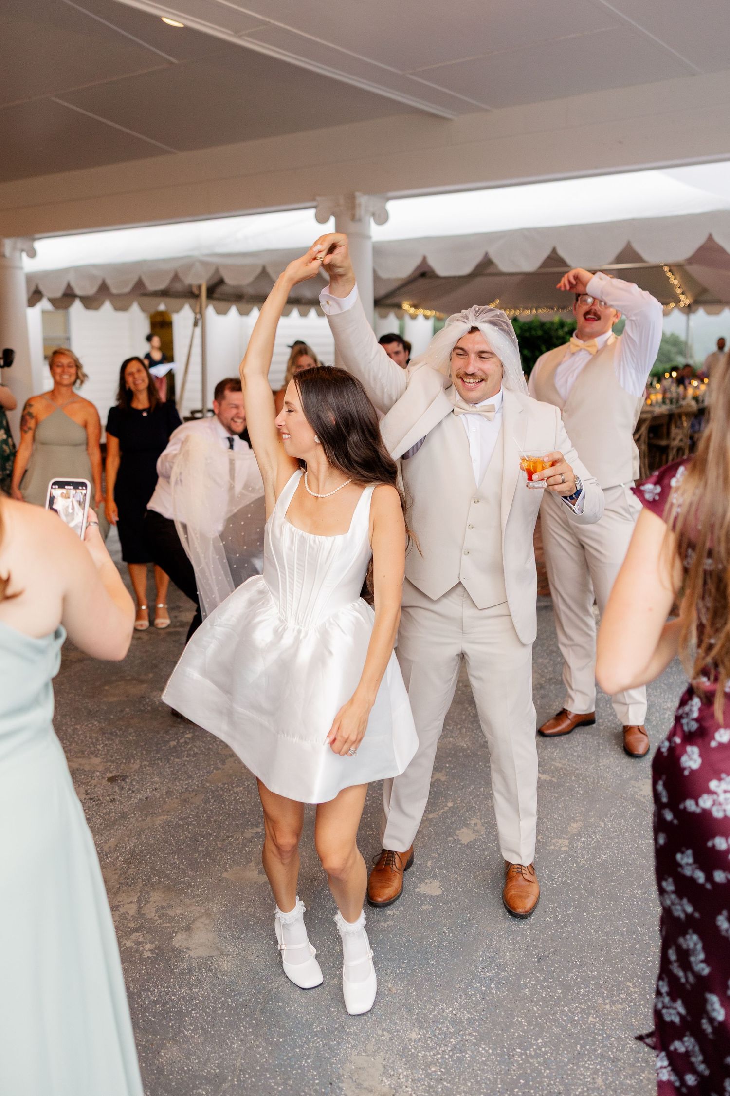 Joyful wedding party dancing in formation wearing white and mint green attire.
