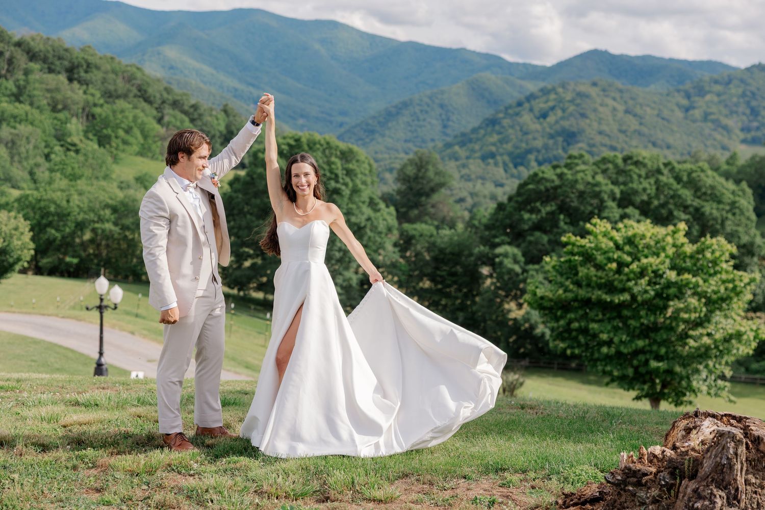 Wedding couple walking together on a scenic mountain path surrounded by lush greenery.
