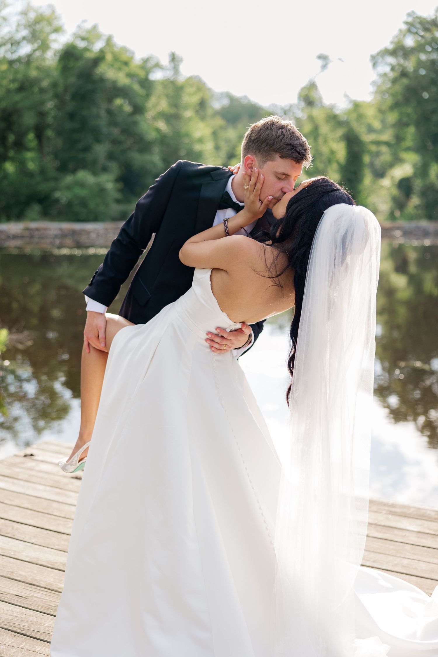 Romantic wedding photo of a couple sharing a romantic dip on a lakeside dock.