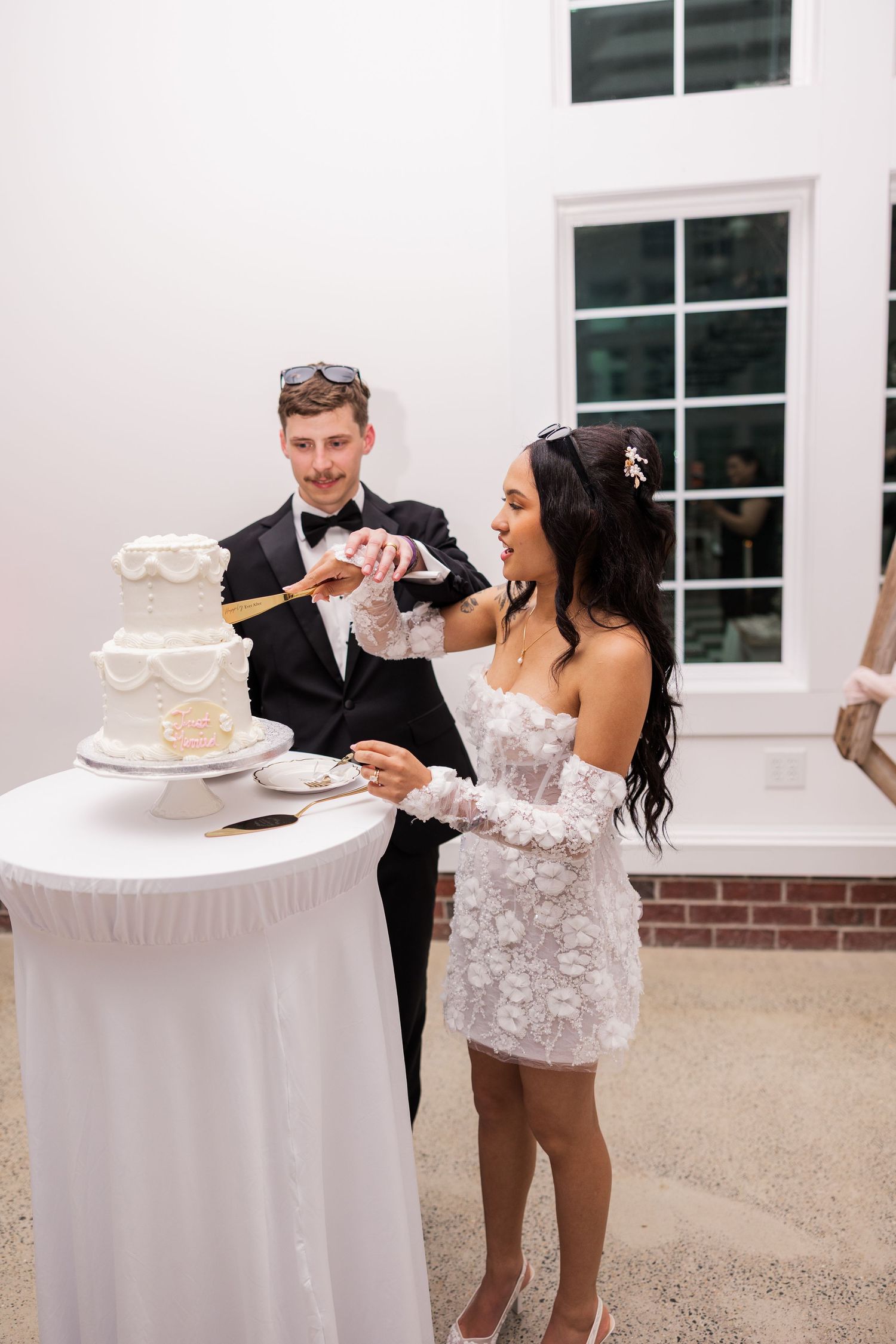 Playful cake cutting moment at wedding reception with white decor.