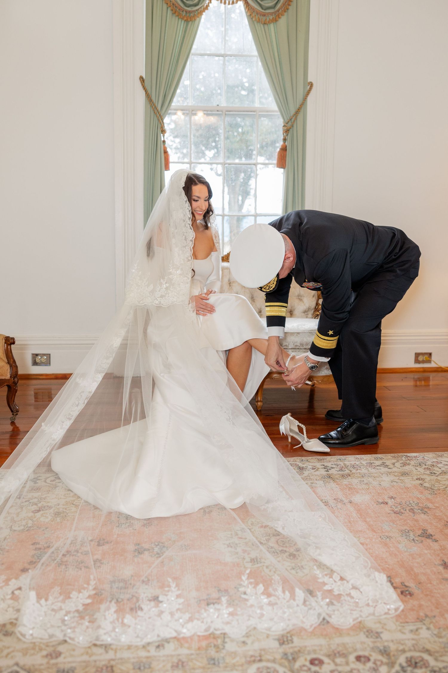 Final wedding dress adjustments being made in an elegant room with mint green curtains.