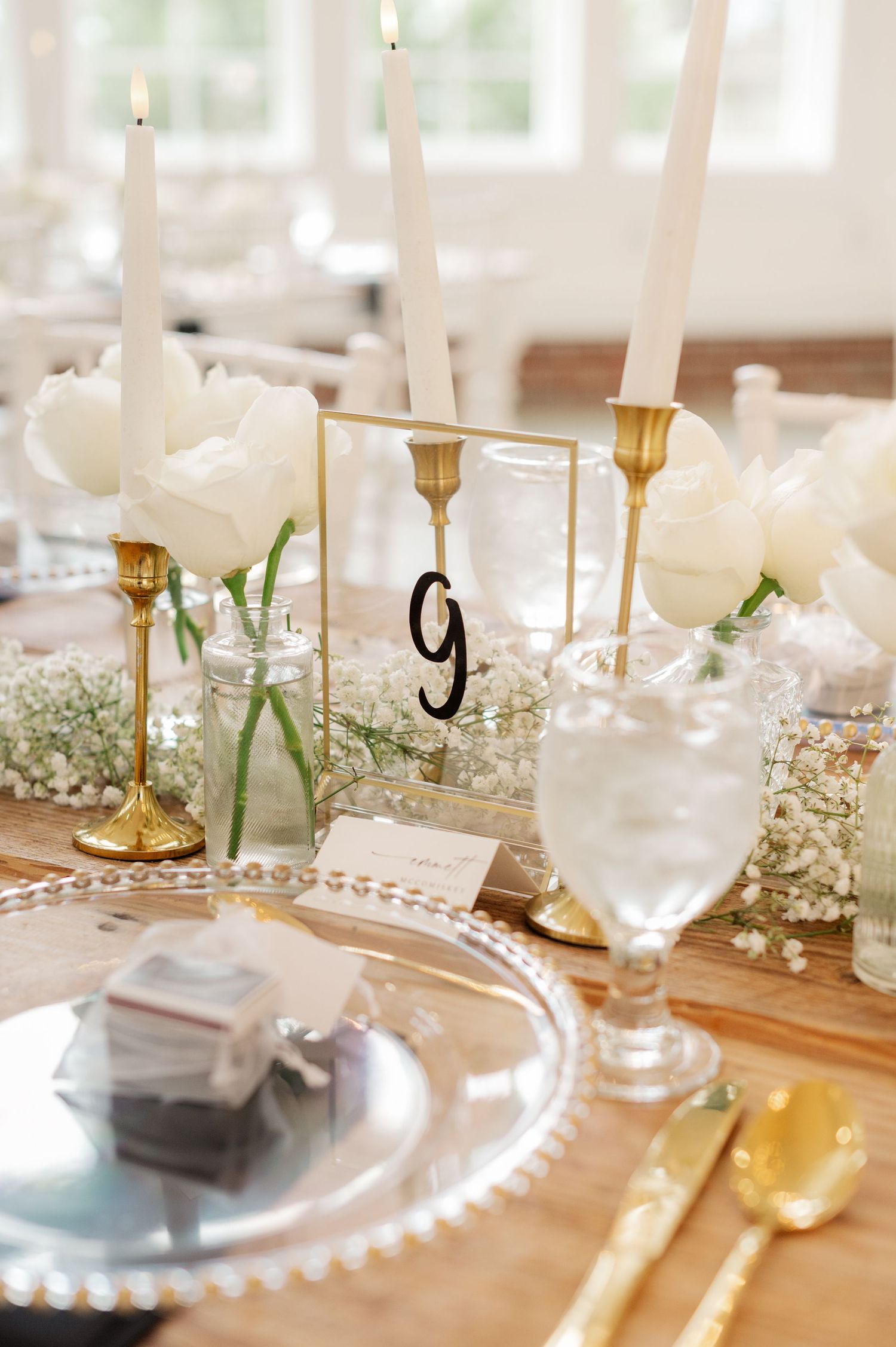 Elegant wedding table setting with white candles, baby's breath flowers and pearl charger plates.